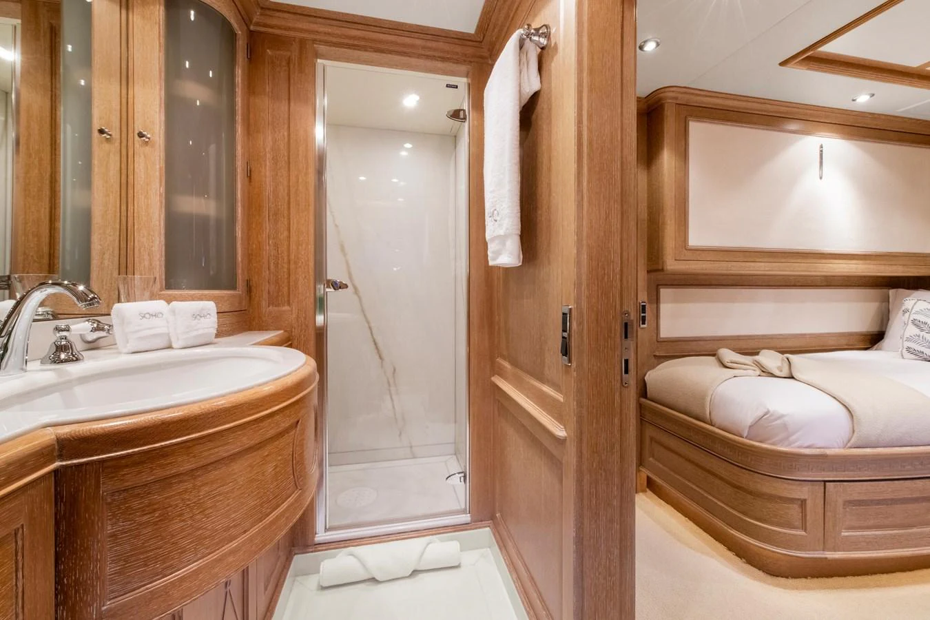 The guest stateroom features a cozy bed and an ensuite bathroom with elegant wood finishes. aboard SOHO Yacht for Sale