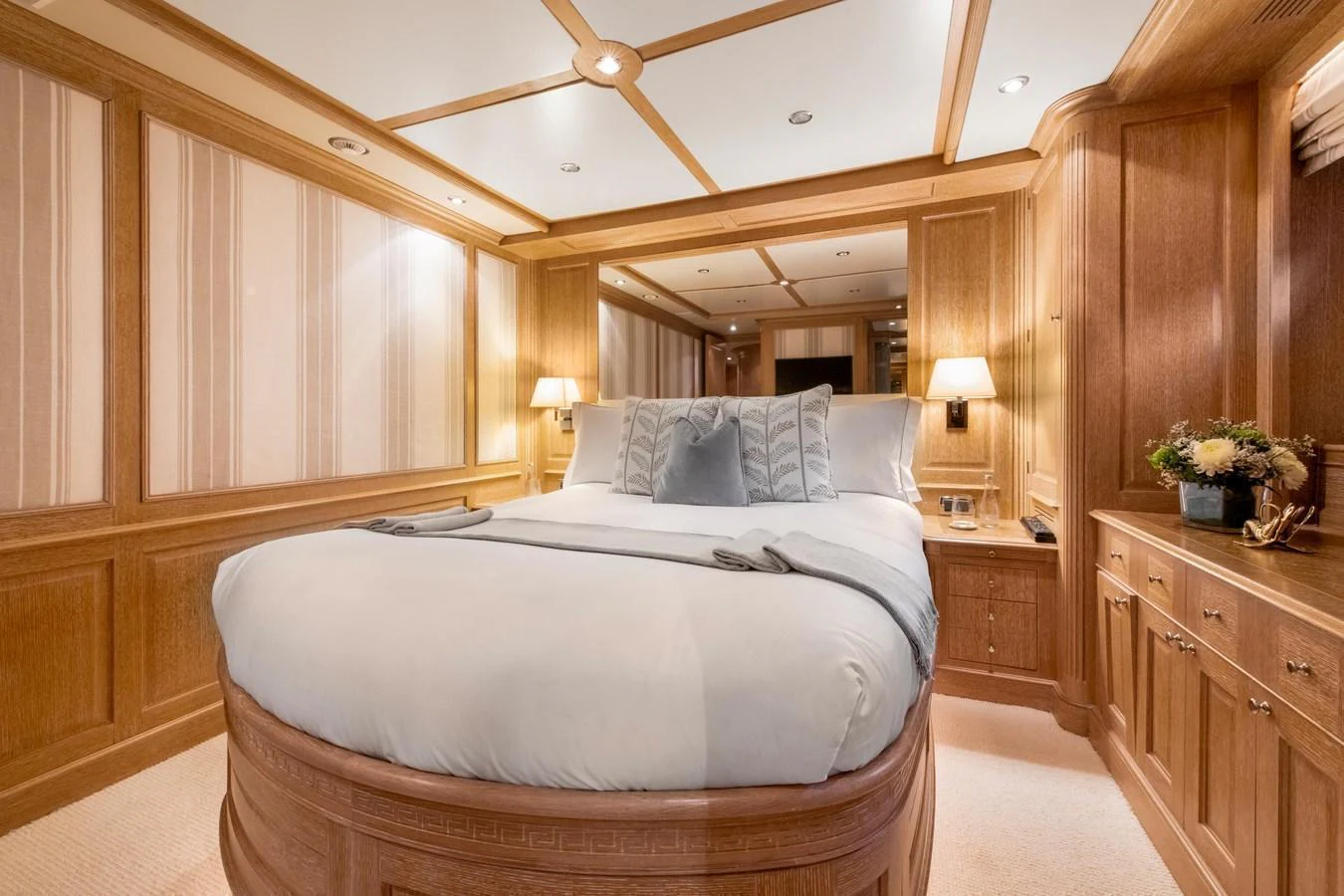 The master stateroom features a luxurious bed with elegant wood paneling and soft lighting. aboard SOHO Yacht for Sale