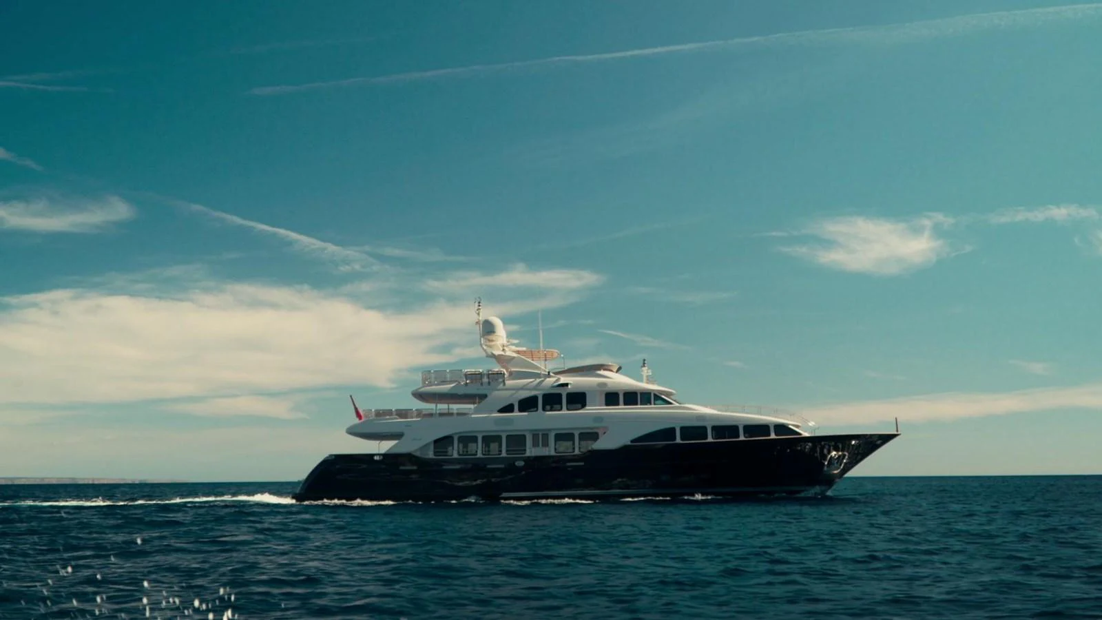 A sleek yacht cruises through calm waters under a clear sky. aboard SOHO Yacht for Sale