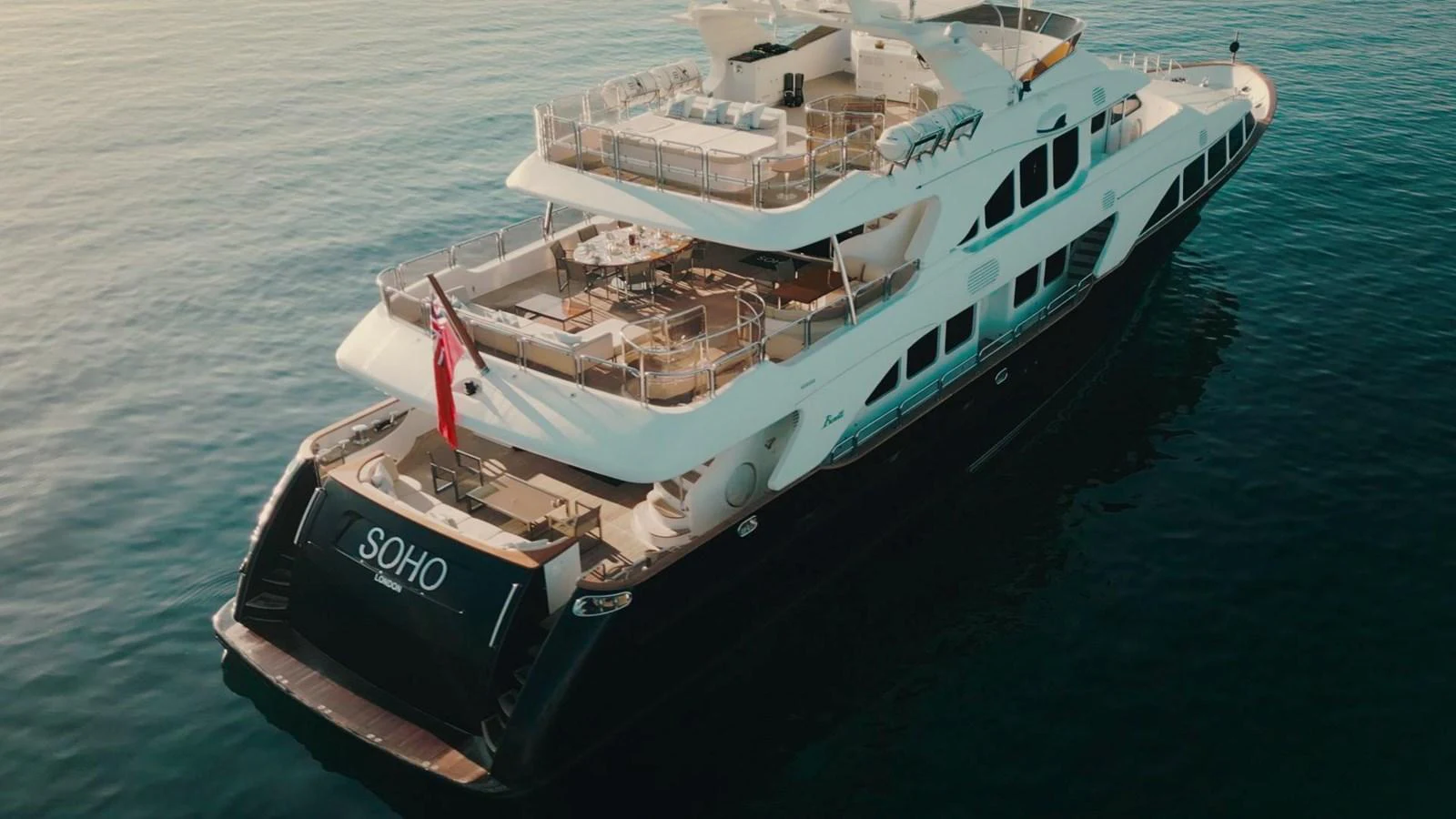 A luxurious yacht with multiple decks and elegant design is seen cruising on calm waters. aboard SOHO Yacht for Sale