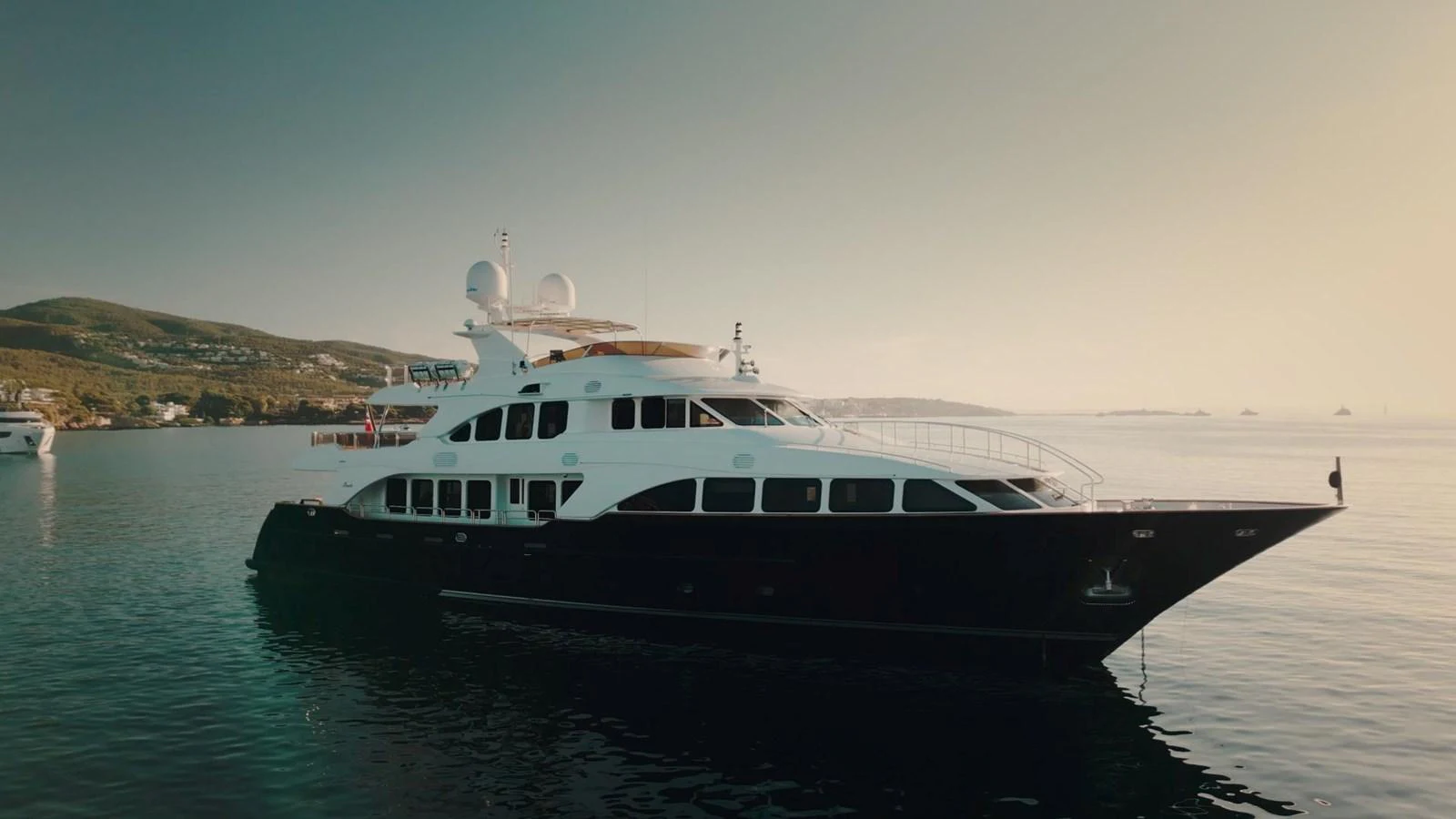 A sleek and elegant yacht is anchored in calm waters, showcasing its luxurious design against a serene backdrop. aboard SOHO Yacht for Sale