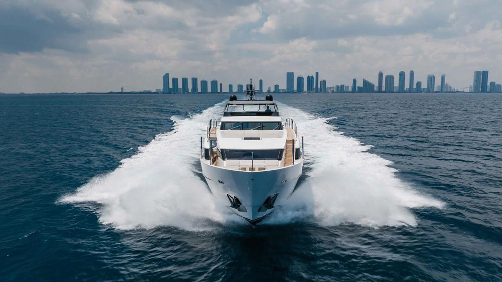 A sleek yacht cruises powerfully through the water with a city skyline in the background. aboard CHAMELEON Yacht for Sale