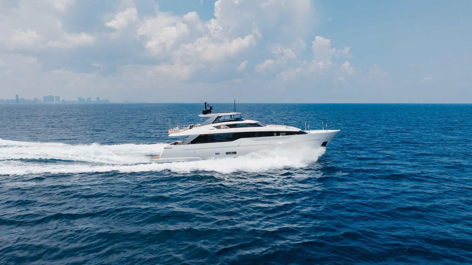 A sleek yacht cruises swiftly across the open sea under a bright sky. aboard CHAMELEON Yacht for Sale