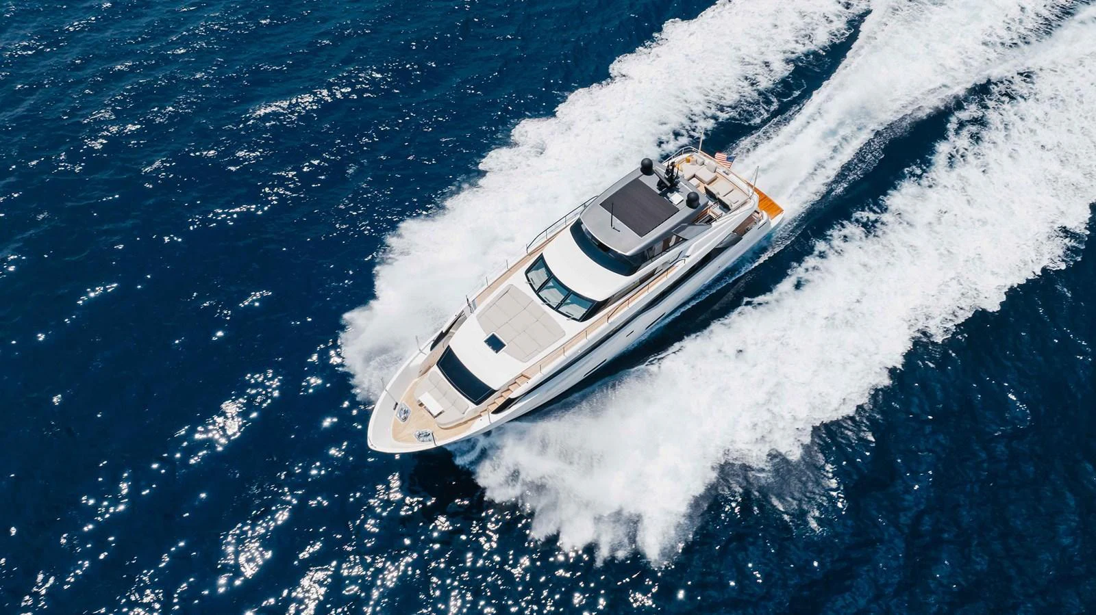 A sleek yacht cruises swiftly through the open water, leaving a trail of white waves behind. aboard CHAMELEON Yacht for Sale