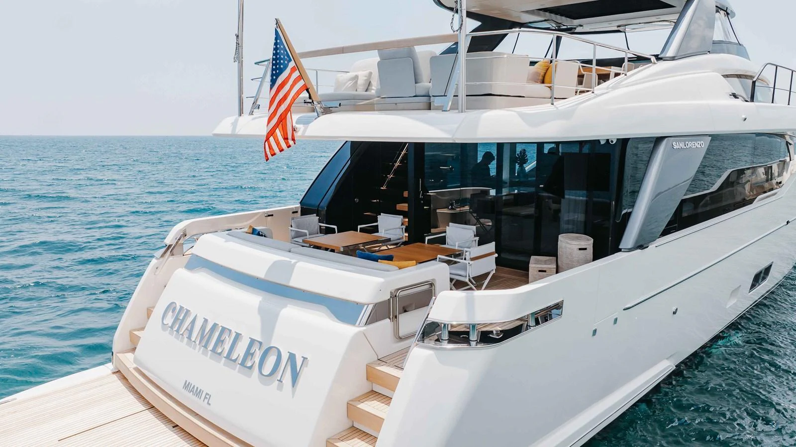 The yacht's aft deck showcases a luxurious lounging area with an inviting swim platform and elegant design. aboard CHAMELEON Yacht for Sale