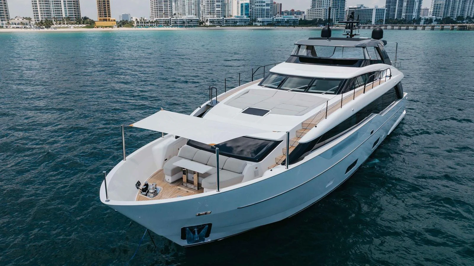 A sleek and modern yacht cruising near a city shoreline, showcasing its luxurious design and spacious deck. aboard CHAMELEON Yacht for Sale