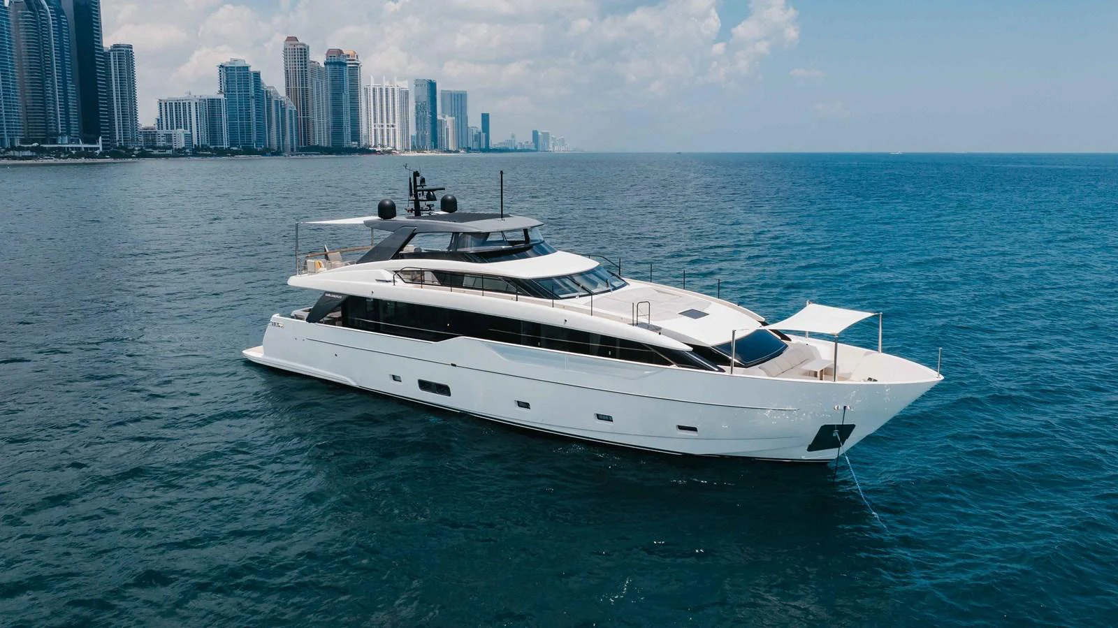 A sleek and modern yacht cruising along a coastal city skyline. aboard CHAMELEON Yacht for Sale