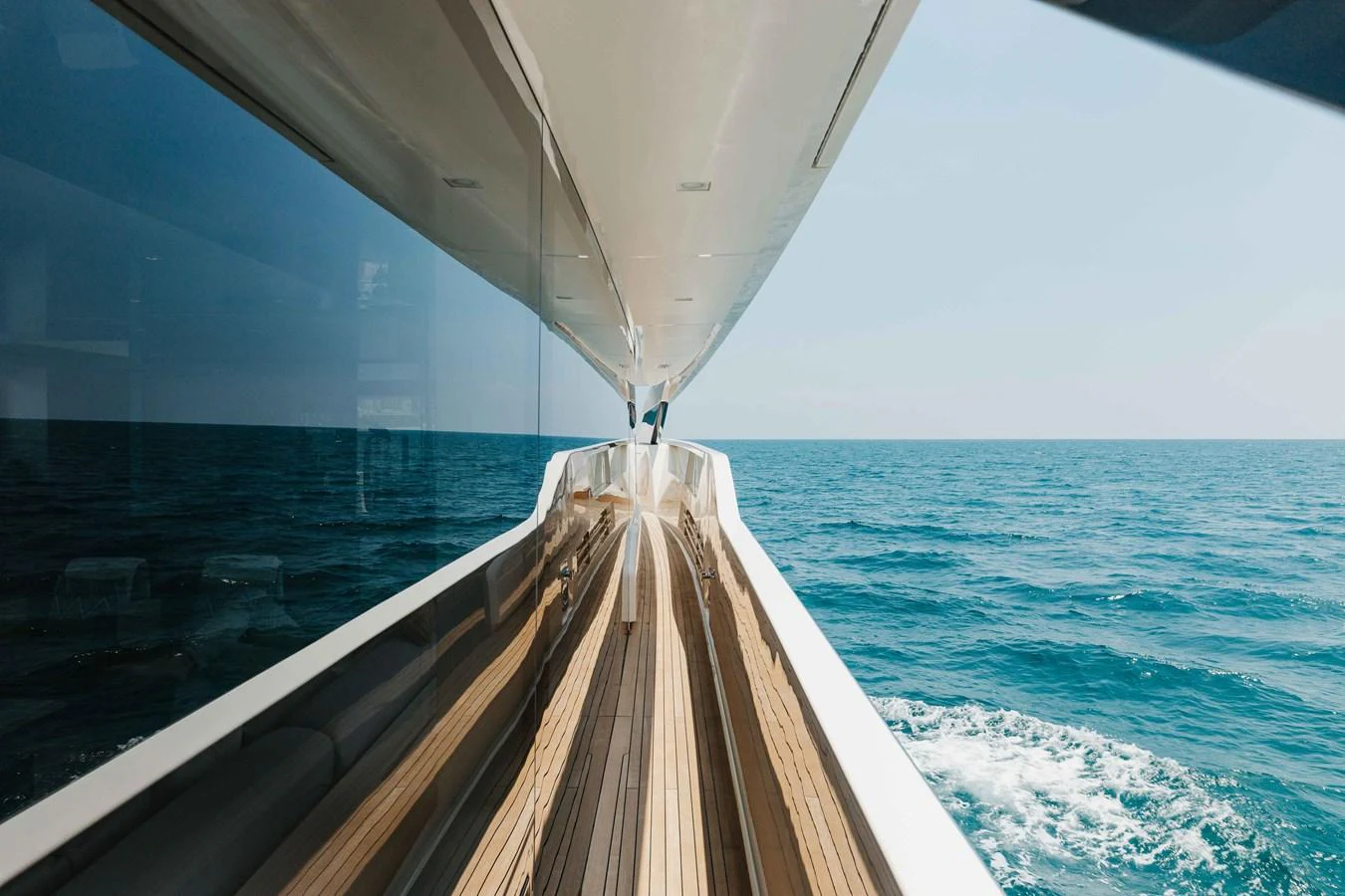 A sleek yacht cruising through the open sea with a view along the side deck. aboard CHAMELEON Yacht for Sale