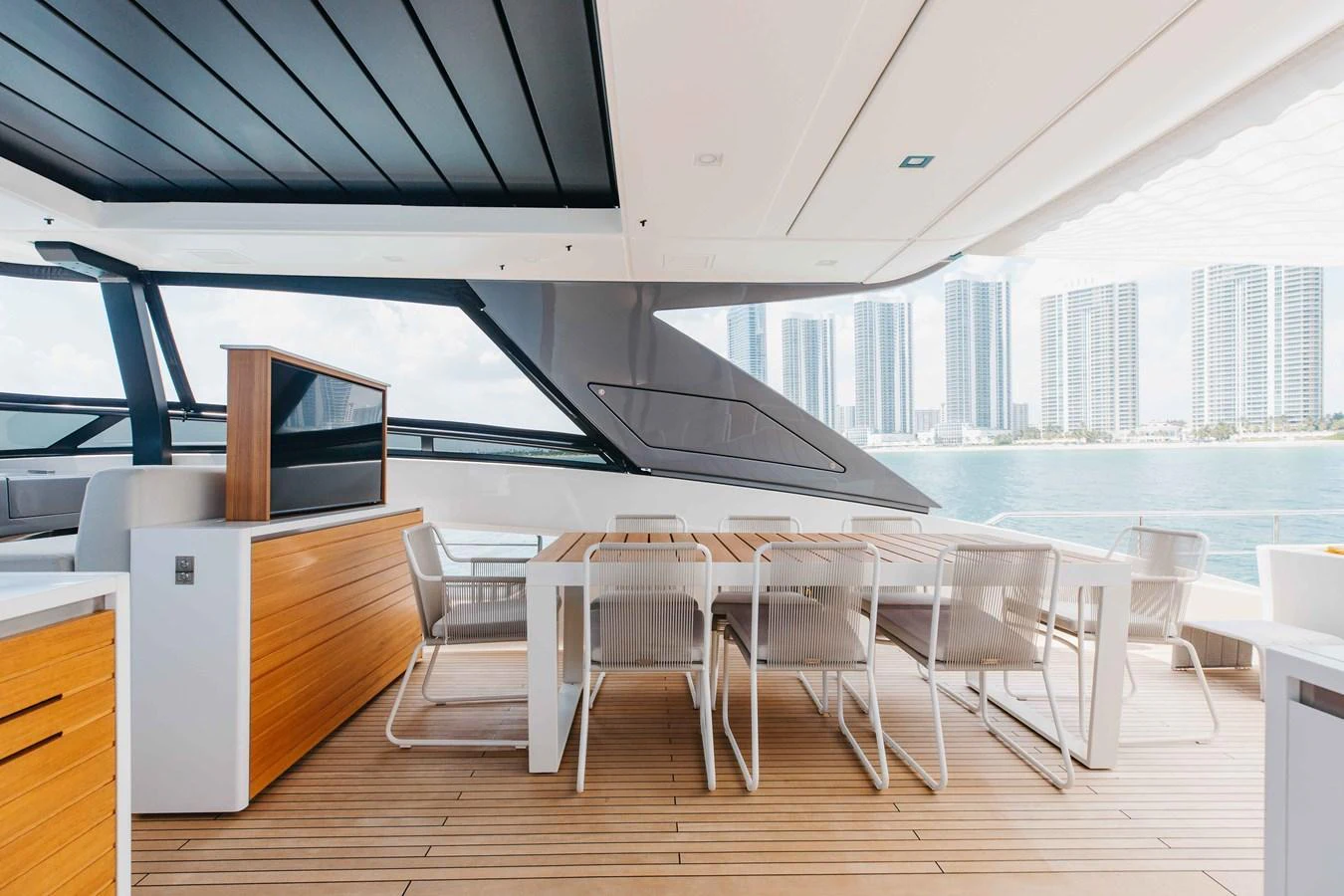 The aft deck features a spacious dining area with modern furnishings and a stunning view of the city skyline. aboard CHAMELEON Yacht for Sale