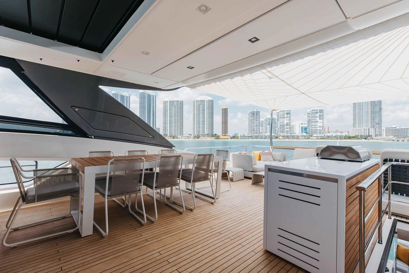 The aft deck features a spacious dining area with modern furnishings and a stunning view of the city skyline. aboard CHAMELEON Yacht for Sale