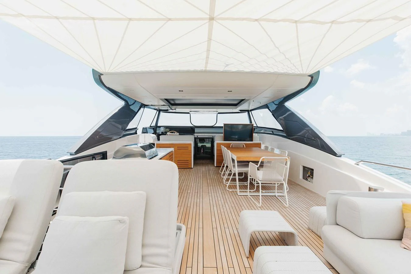 The flybridge offers a spacious and luxurious outdoor living area with comfortable seating and a dining table under a canopy. aboard CHAMELEON Yacht for Sale