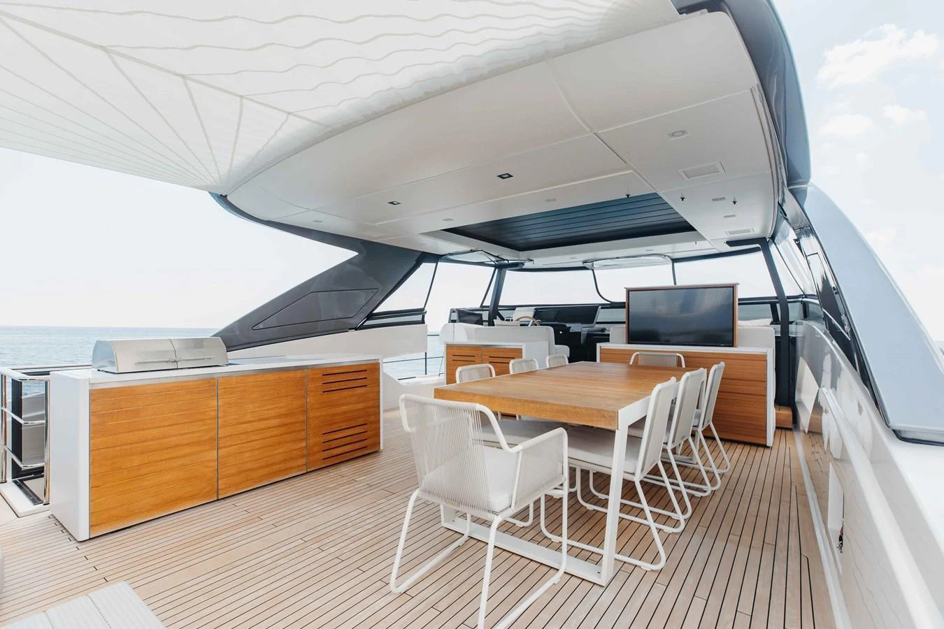 The aft deck features a spacious dining area with modern furnishings and a retractable sunshade. aboard CHAMELEON Yacht for Sale