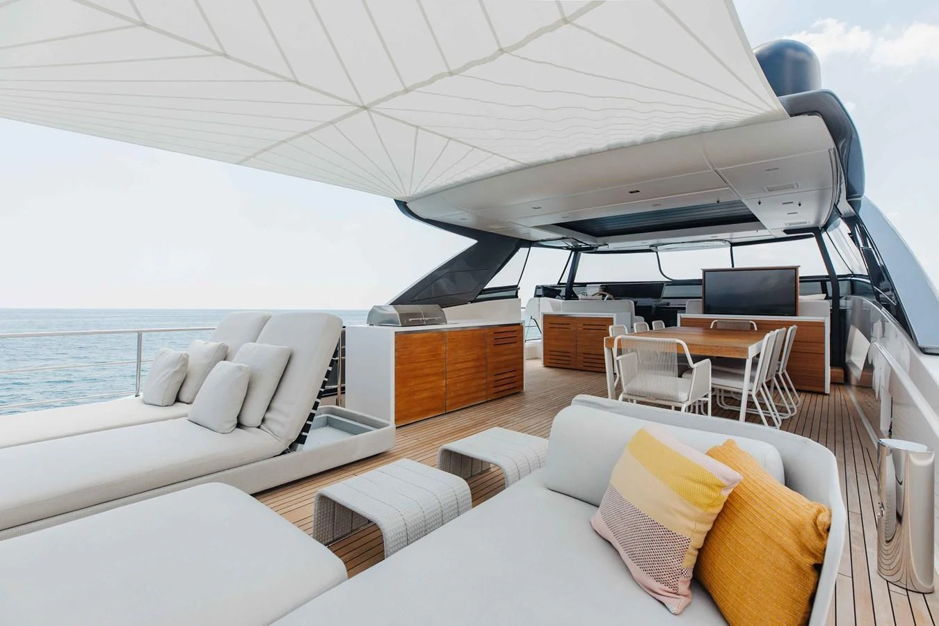 The flybridge offers a luxurious outdoor living space with comfortable seating, sun loungers, and a dining area under a shade canopy. aboard CHAMELEON Yacht for Sale