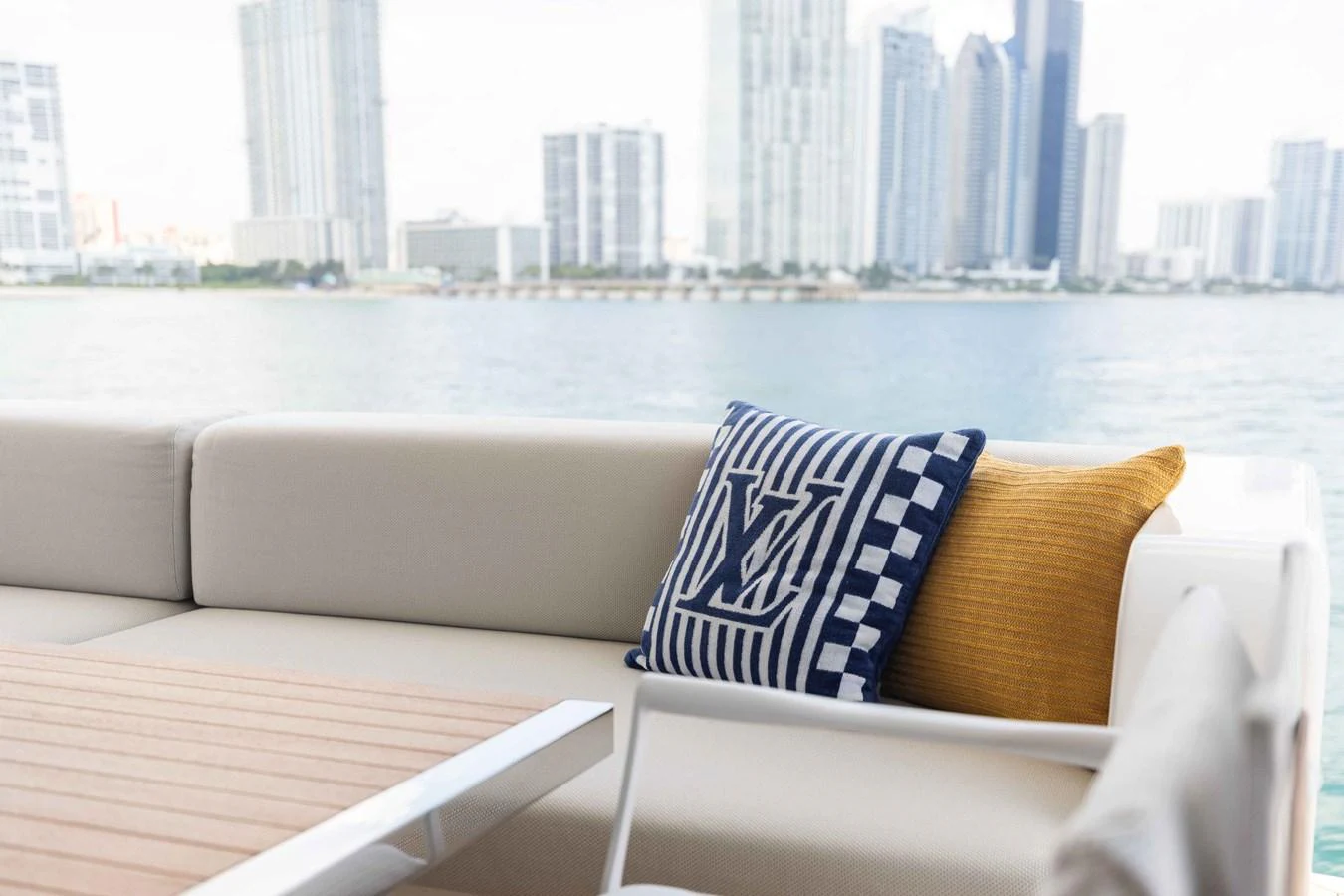 A stylish aft deck seating area with plush cushions and a scenic city skyline view. aboard CHAMELEON Yacht for Sale