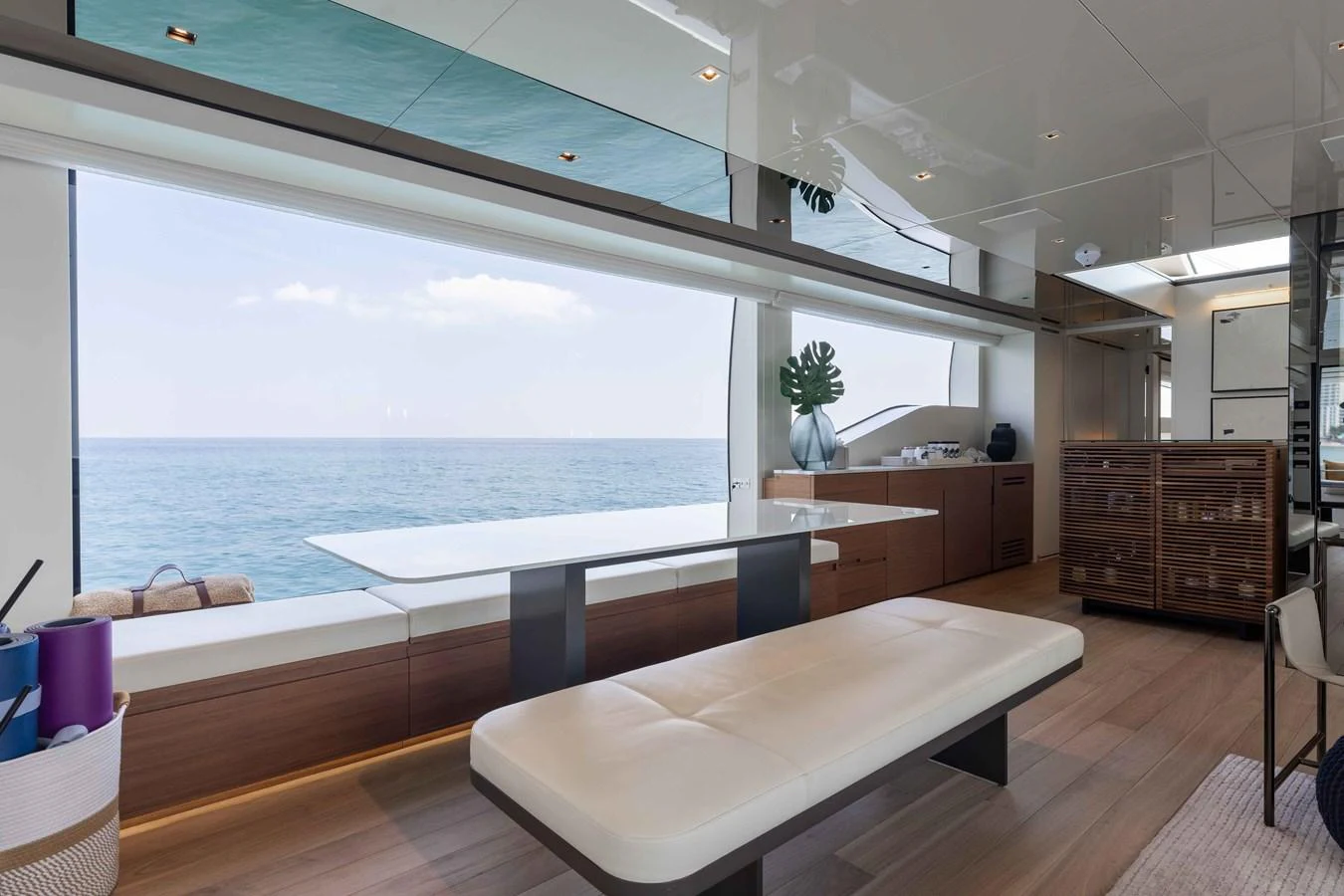 The yacht's interior features a sleek dining area with a panoramic ocean view. aboard CHAMELEON Yacht for Sale