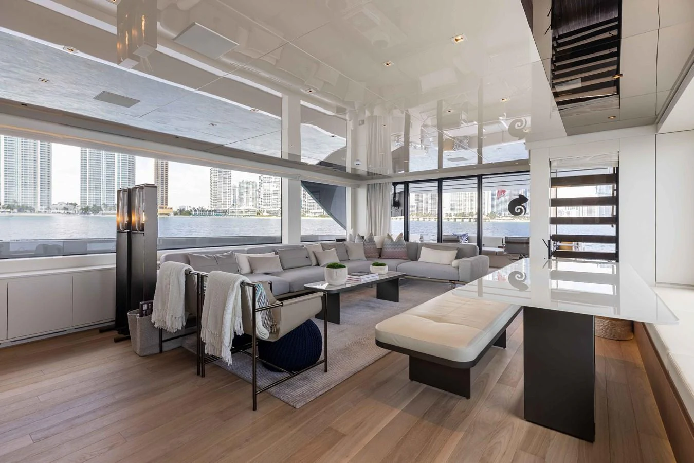 The spacious salon features modern furnishings and expansive windows with stunning city views. aboard CHAMELEON Yacht for Sale