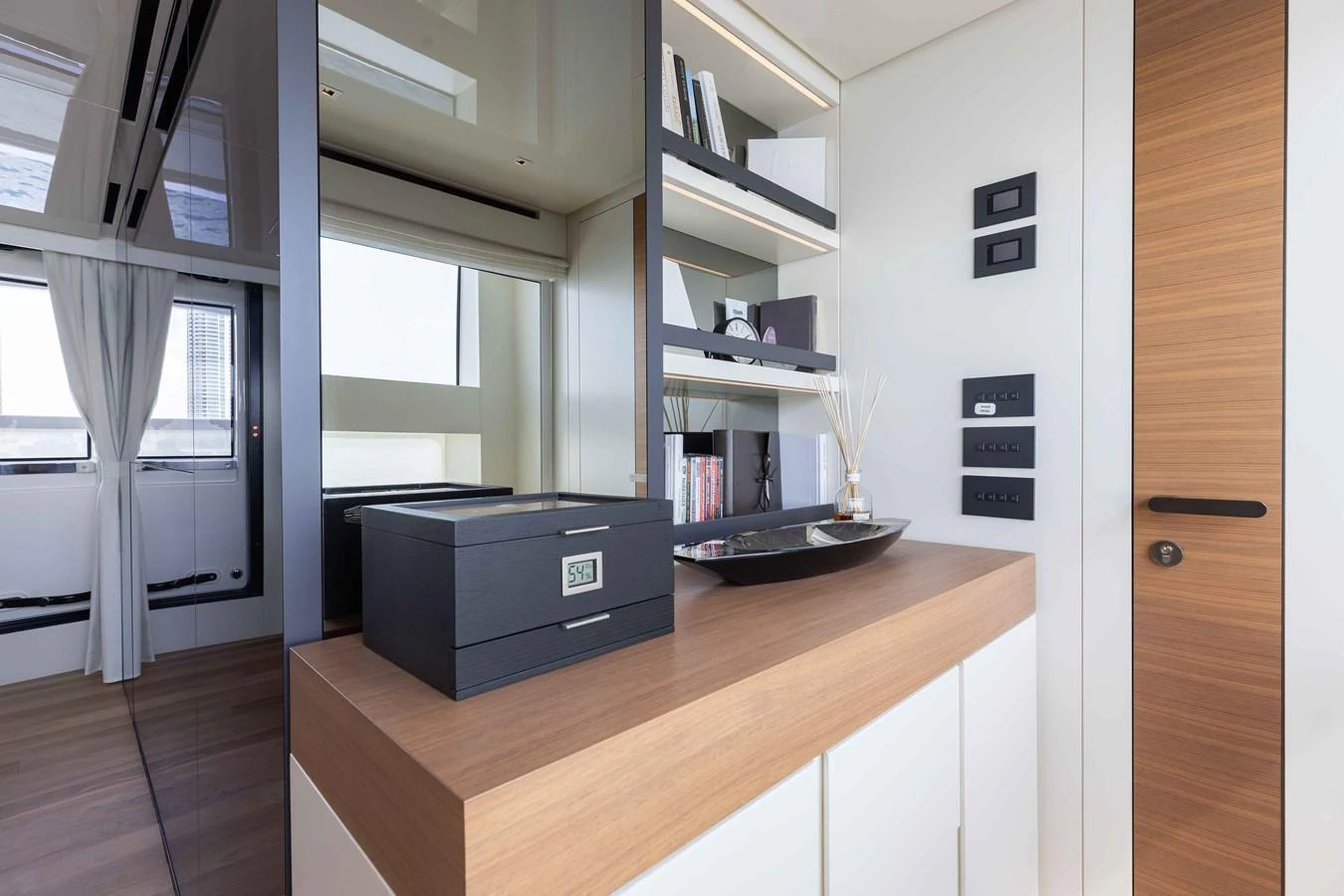 A modern interior space featuring a sleek wooden countertop and built-in shelving with decorative items. aboard CHAMELEON Yacht for Sale