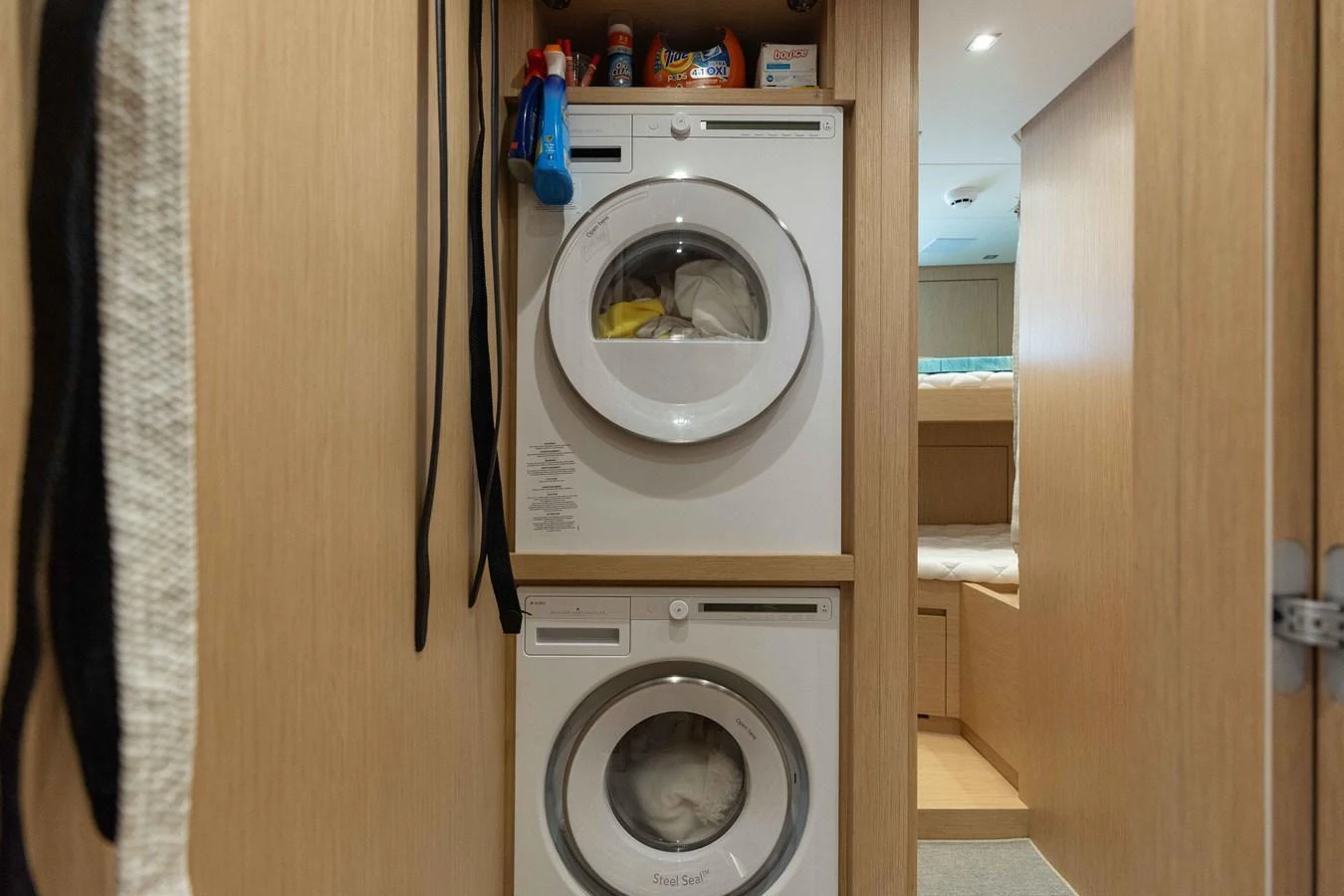 The yacht features a compact and efficient laundry area with stacked washer and dryer units. aboard CHAMELEON Yacht for Sale