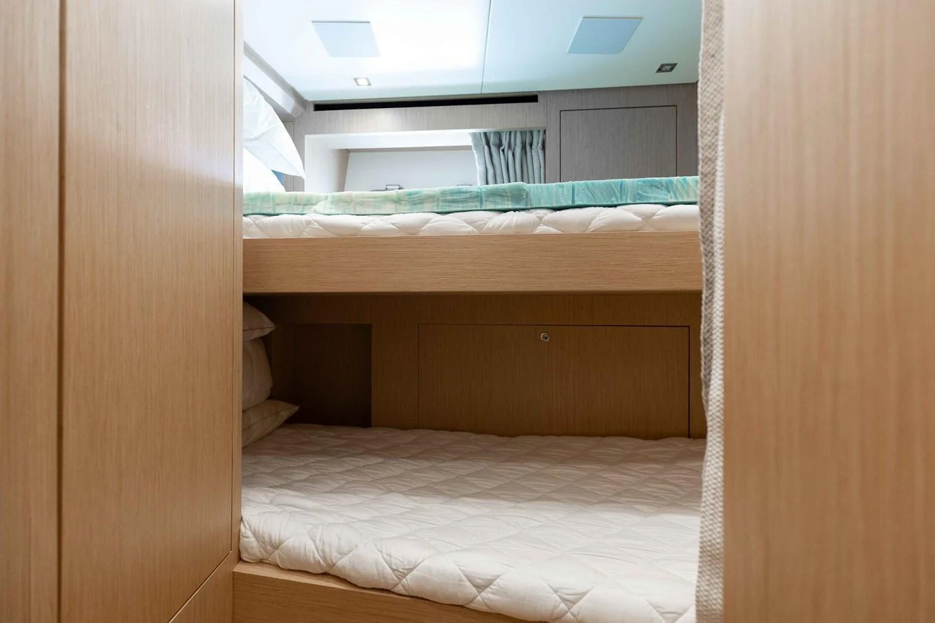 The image showcases a cozy bunk cabin with neatly arranged bedding and modern wooden finishes. aboard CHAMELEON Yacht for Sale