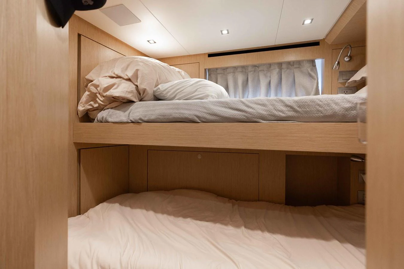 A cozy bunk cabin with light wood finishes and soft bedding. aboard CHAMELEON Yacht for Sale