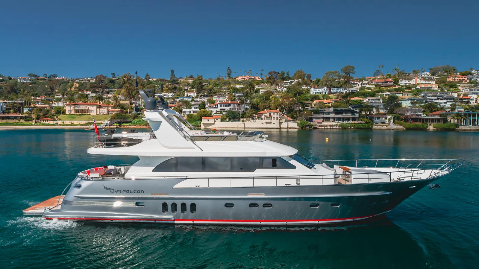 A sleek and modern yacht cruises along a picturesque coastline under a clear blue sky. aboard TEST NAME Yacht for Sale
