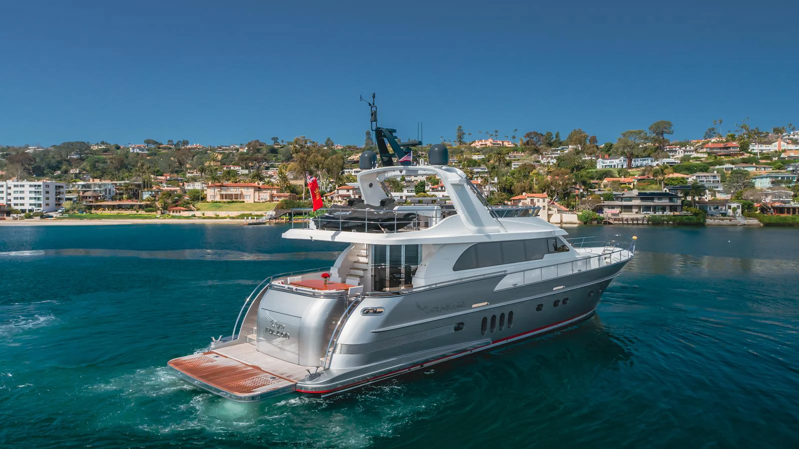 A sleek yacht cruises through pristine waters with a scenic coastal backdrop. aboard TEST NAME Yacht for Sale