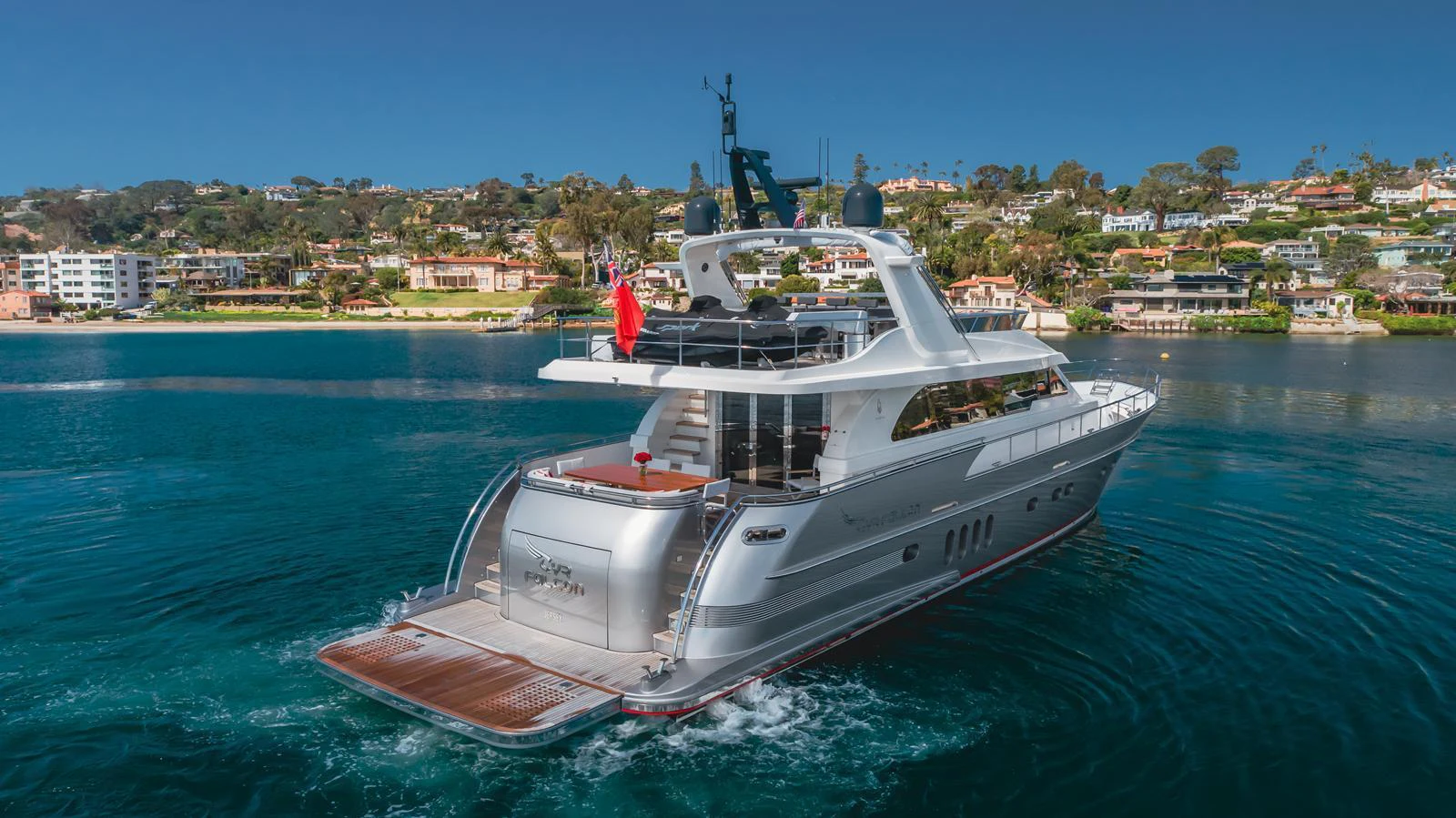 A sleek yacht cruises through calm waters with a scenic coastal backdrop. aboard TEST NAME Yacht for Sale