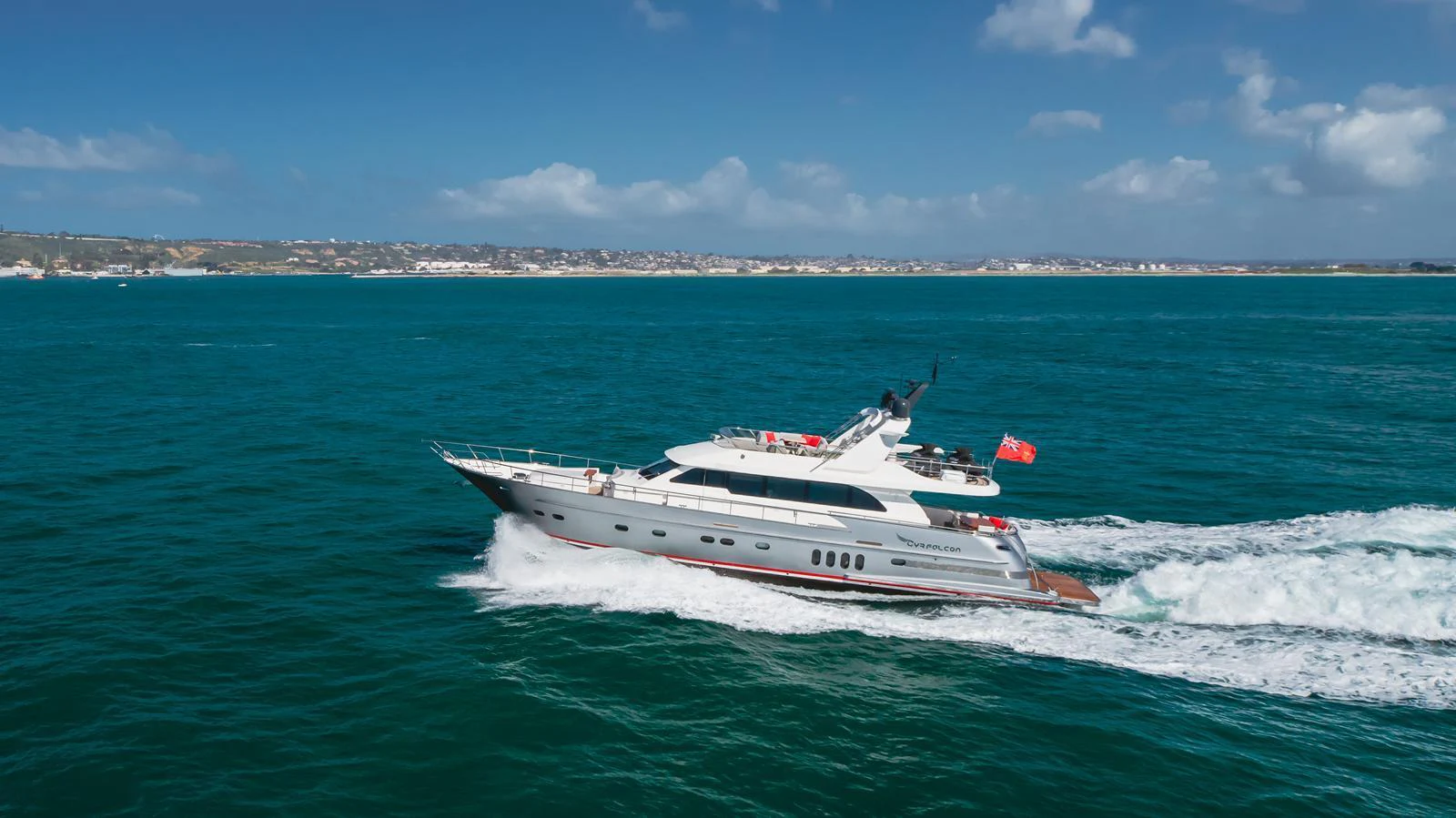 A sleek yacht cruises through vibrant blue waters under a clear sky. aboard TEST NAME Yacht for Sale