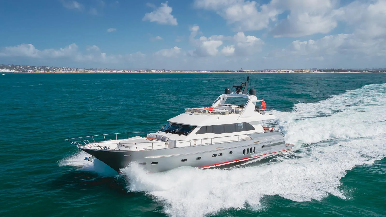 A sleek yacht cruises through vibrant blue waters under a bright sky. aboard TEST NAME Yacht for Sale
