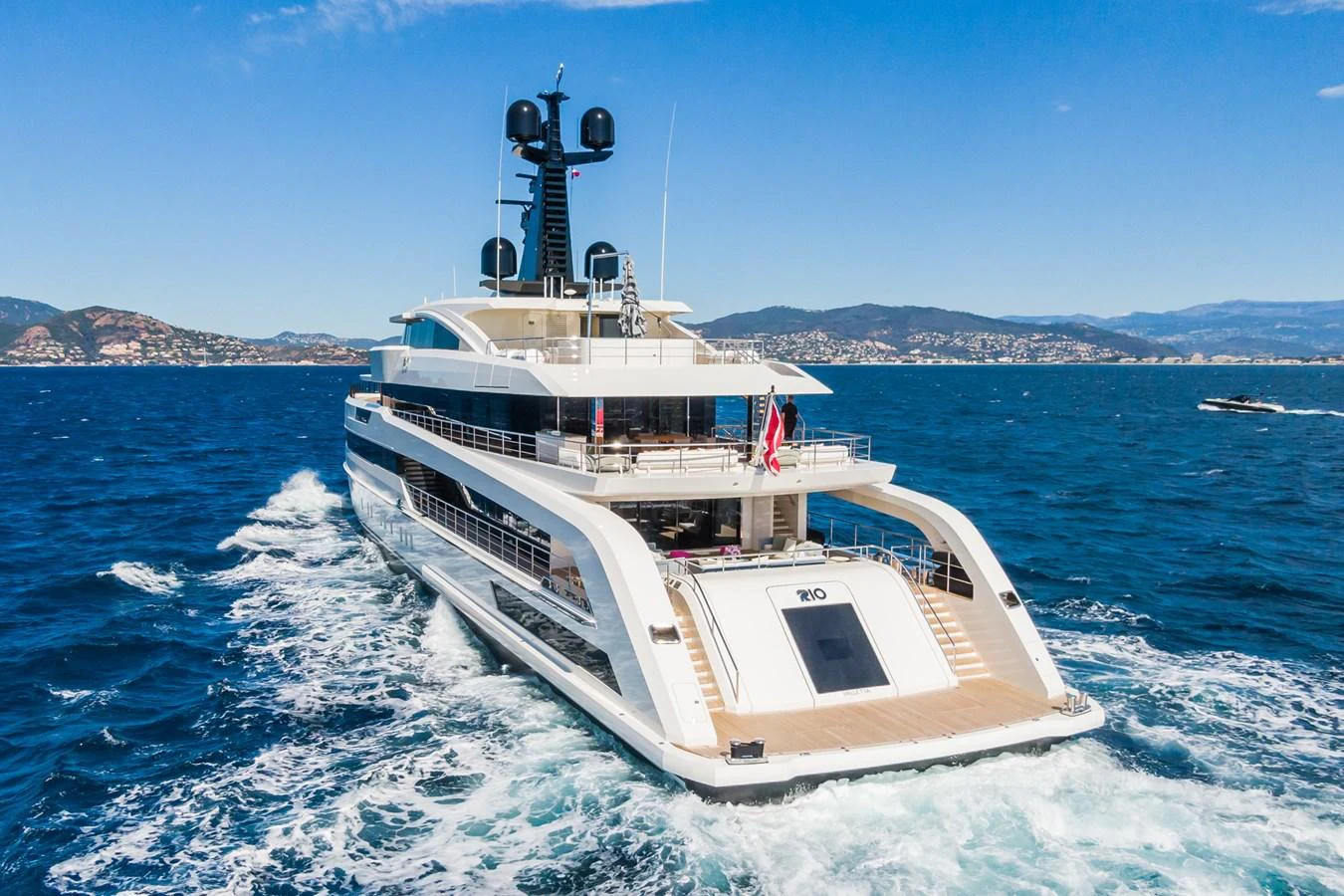A luxurious yacht cruising through clear blue waters with a scenic coastline in the background. aboard RIO Yacht for Sale