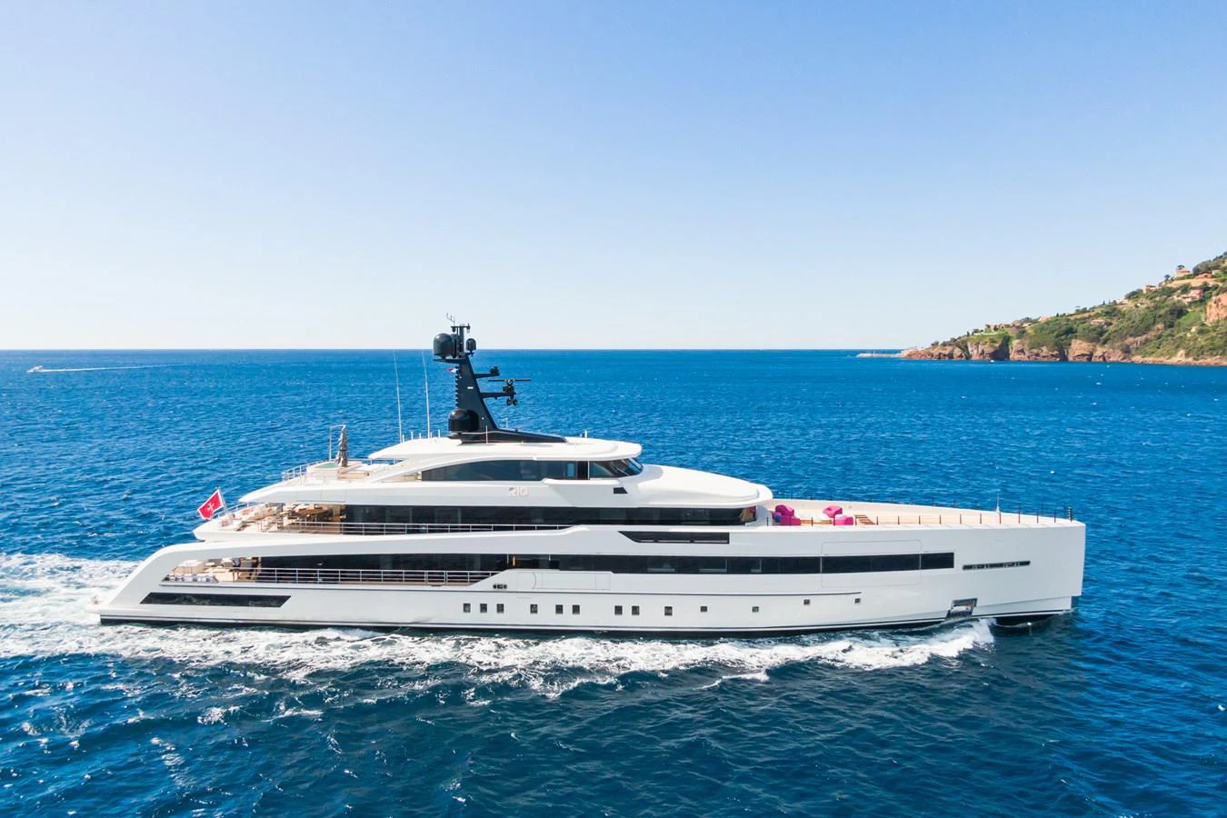 A sleek and modern yacht cruising on the open sea with a scenic coastline in the background. aboard RIO Yacht for Sale