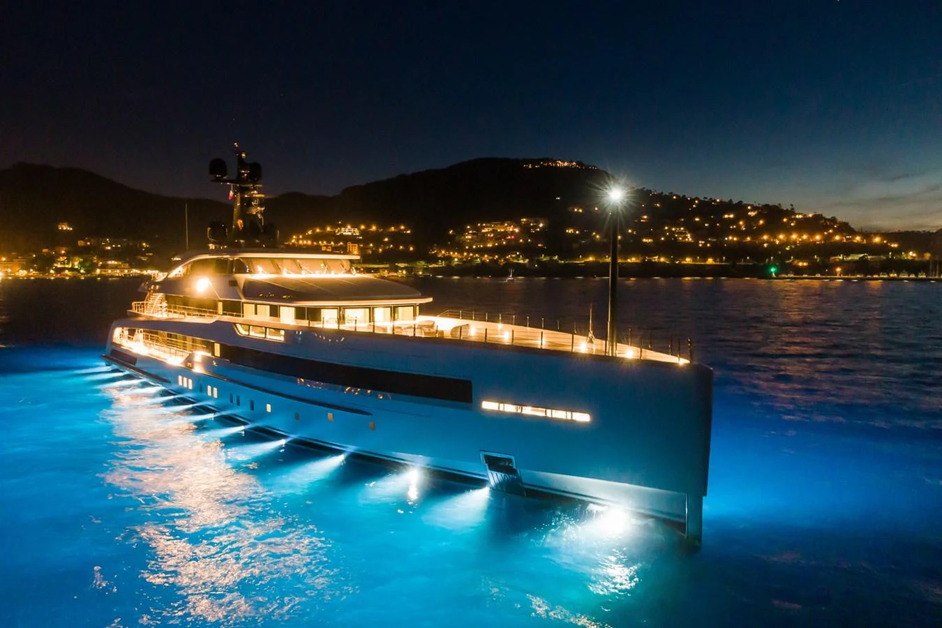A stunning yacht illuminated at night, showcasing its sleek design and elegant lighting against a serene coastal backdrop. aboard RIO Yacht for Sale