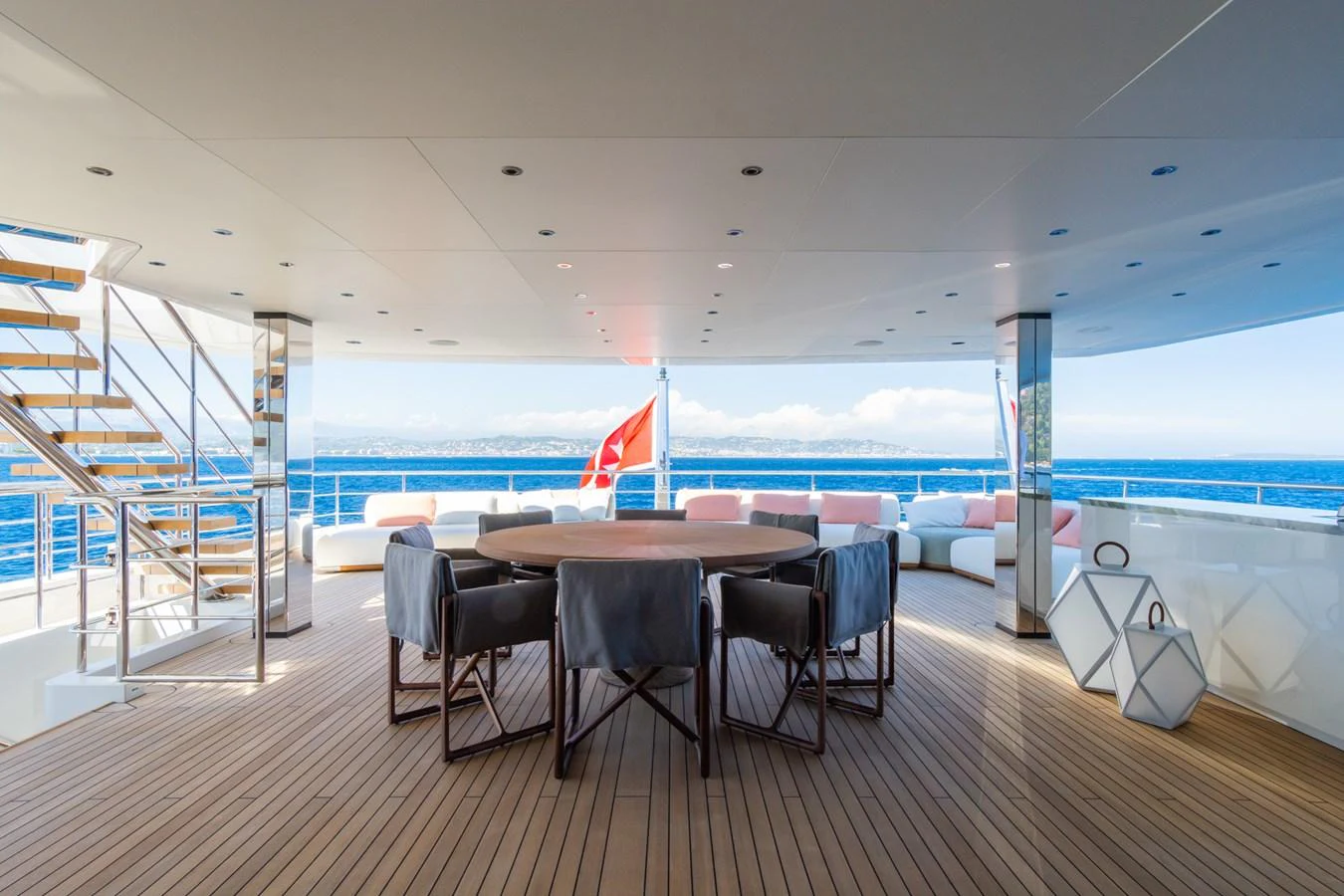 The aft deck features a spacious seating area with a round dining table, perfect for enjoying meals with a view of the sea. aboard RIO Yacht for Sale