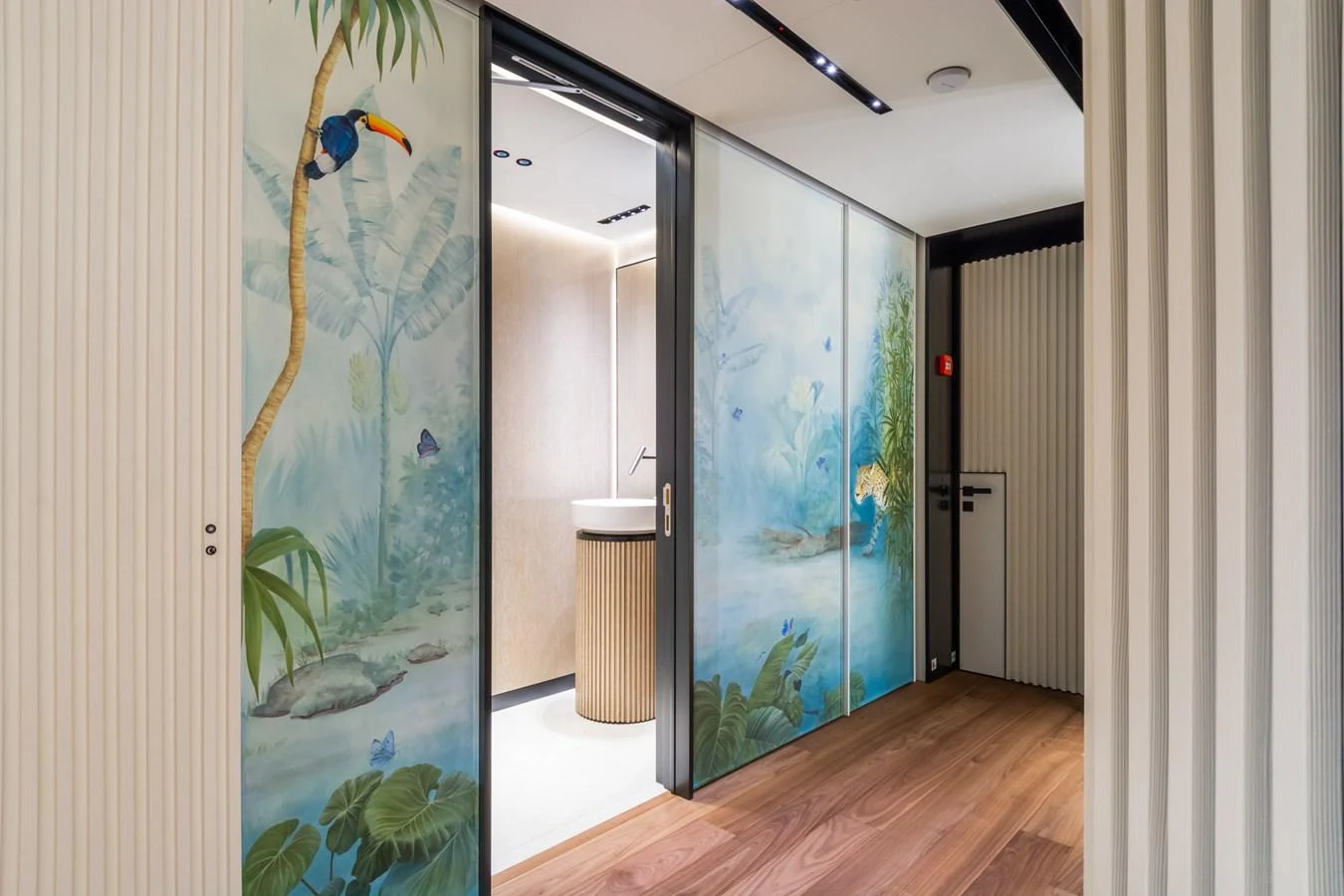The interior features a serene hallway with tropical-themed decor and a modern washbasin area. aboard RIO Yacht for Sale