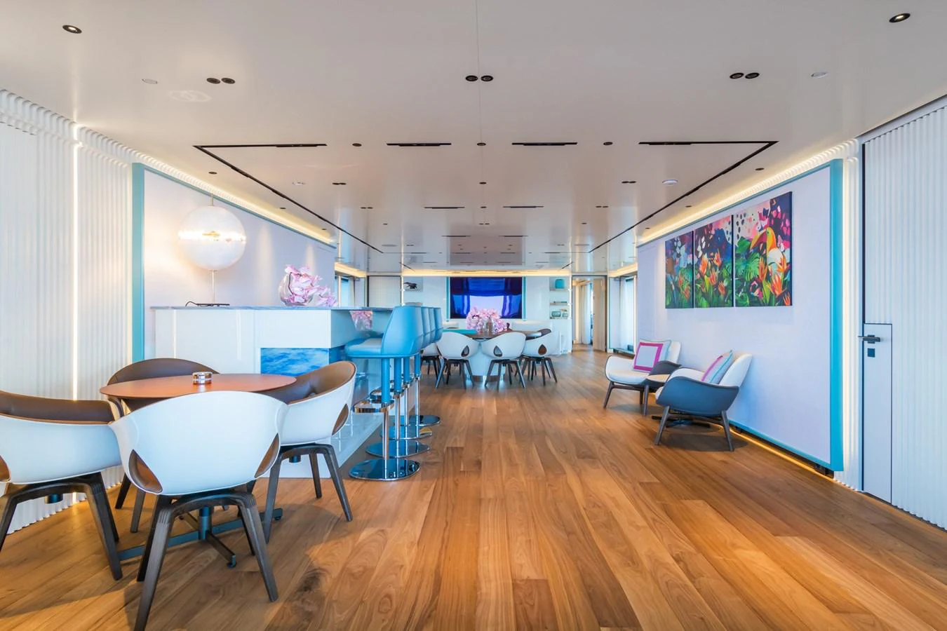 The yacht's interior features a spacious and modern lounge area with stylish seating and vibrant artwork. aboard RIO Yacht for Sale