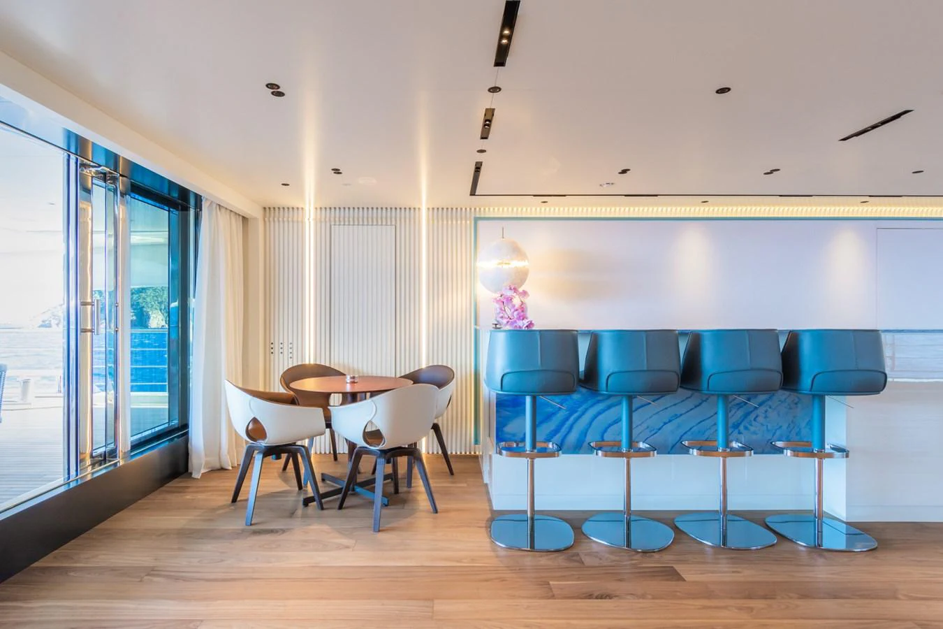 The salon features a modern dining area with a round table and stylish bar seating, offering a luxurious and inviting atmosphere. aboard RIO Yacht for Sale