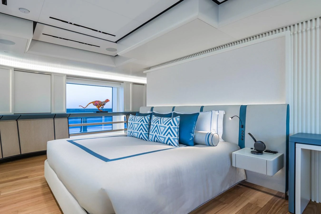 The master stateroom features a spacious bed with elegant blue and white decor, offering a serene ocean view. aboard RIO Yacht for Sale