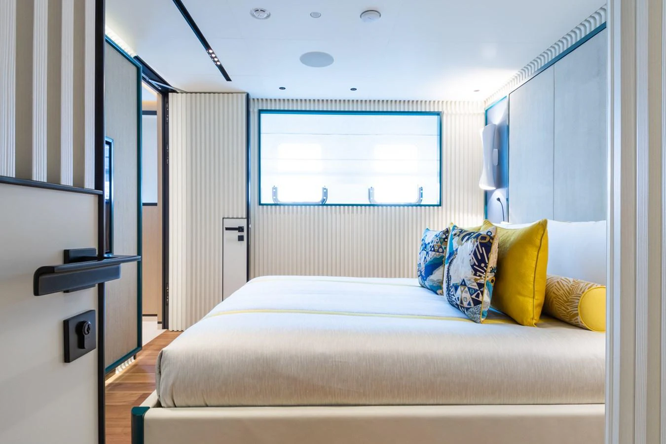A luxurious stateroom featuring a large bed with vibrant pillows and modern decor. aboard RIO Yacht for Sale