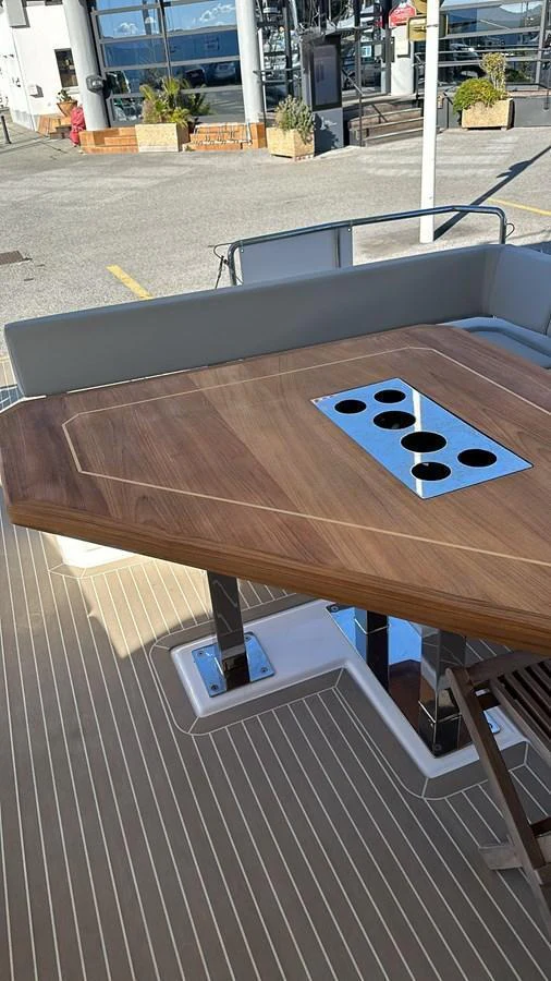 A close-up view of a wooden table with integrated cup holders on the aft deck. aboard LEOPARD 28M Yacht for Sale