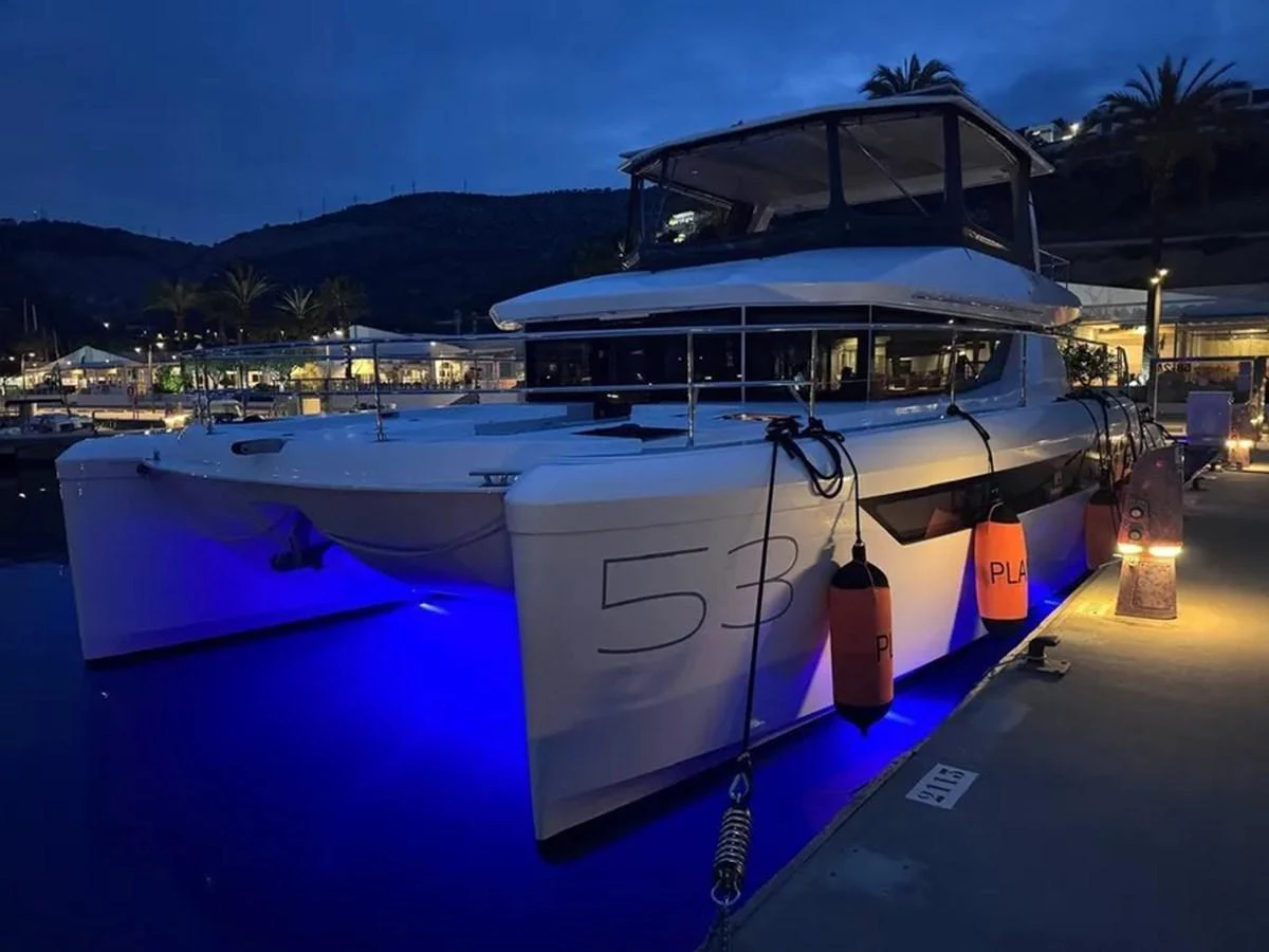 A sleek yacht is docked at a marina, illuminated by blue underwater lights in the evening. aboard LEOPARD 28M Yacht for Sale
