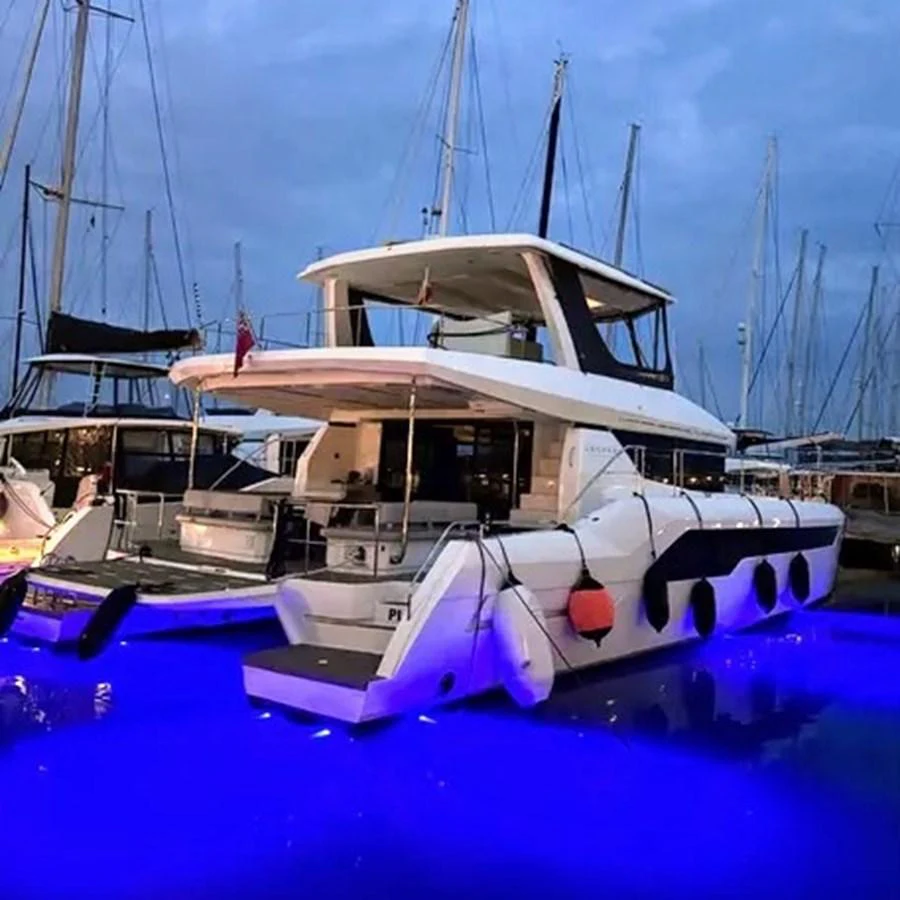 A sleek yacht is docked at a marina, illuminated by vibrant blue underwater lights. aboard LEOPARD 28M Yacht for Sale