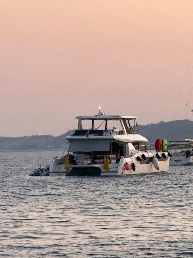 A yacht is anchored on calm waters during sunset, showcasing its spacious aft deck and multiple amenities. aboard LEOPARD 28M Yacht for Sale