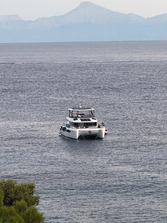 A yacht is seen cruising on calm waters with a mountainous backdrop. aboard LEOPARD 28M Yacht for Sale