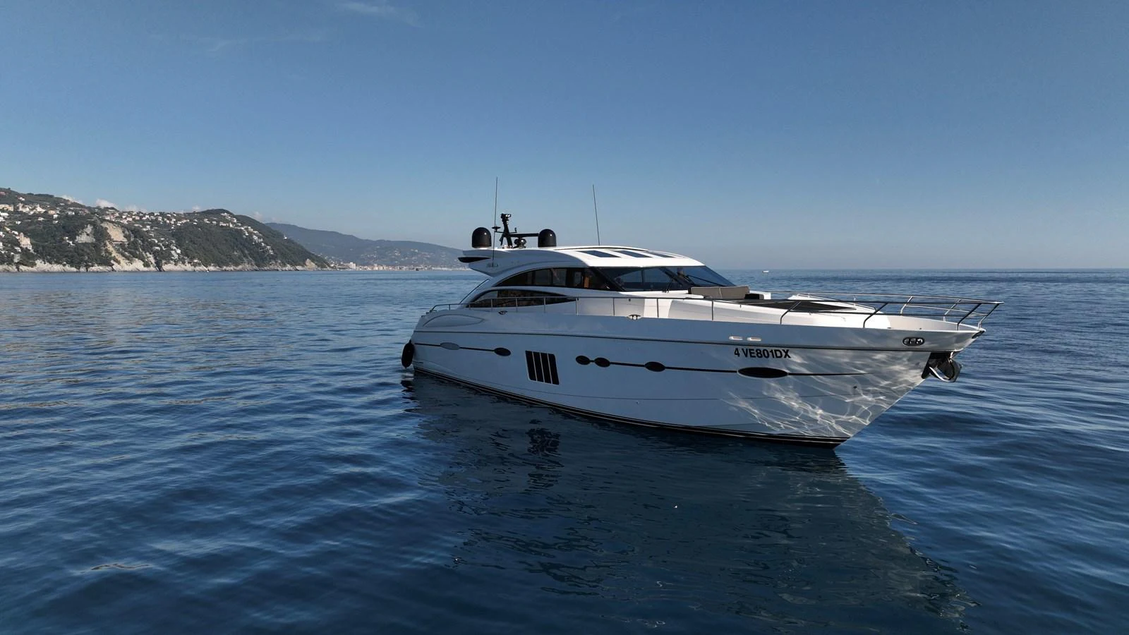 A sleek and modern yacht glides gracefully on calm blue waters with a picturesque coastline in the background. aboard GIA GIA' Yacht for Sale