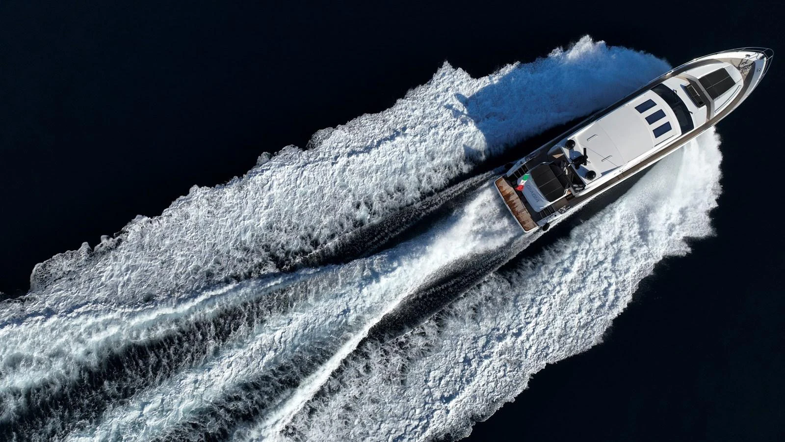A sleek yacht cruises swiftly through the water, leaving a dynamic wake behind. aboard GIA GIA' Yacht for Sale