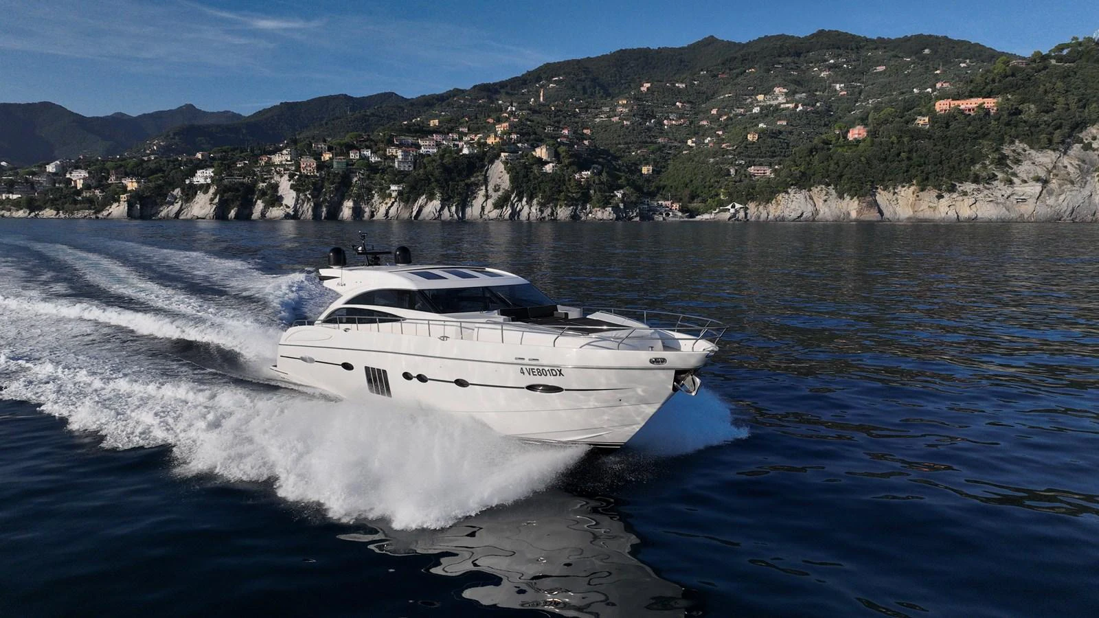 A sleek yacht cruises swiftly on calm waters with a scenic coastal backdrop. aboard GIA GIA' Yacht for Sale