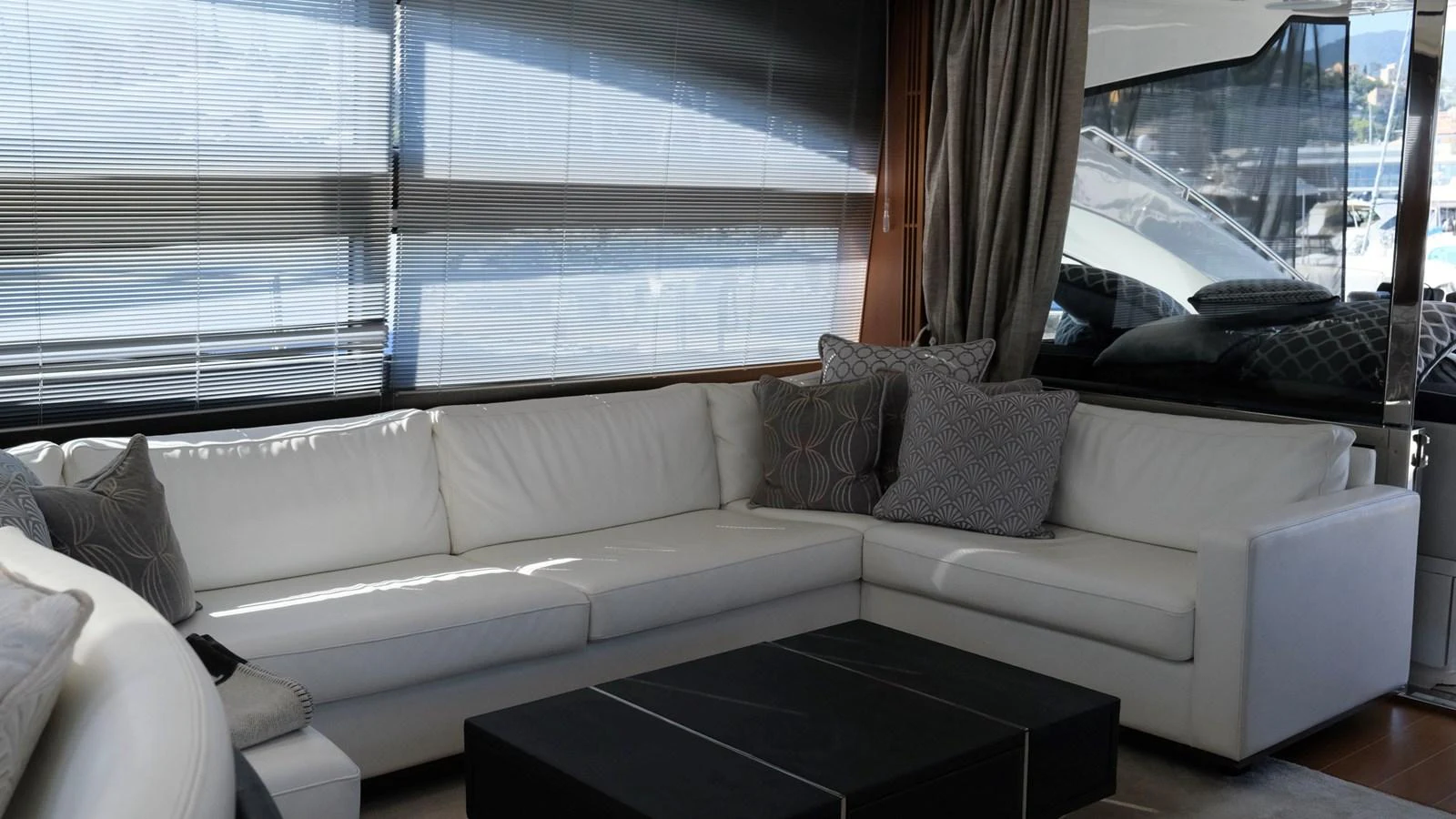The salon features a luxurious white sectional sofa with patterned throw pillows and a sleek black coffee table. aboard GIA GIA' Yacht for Sale