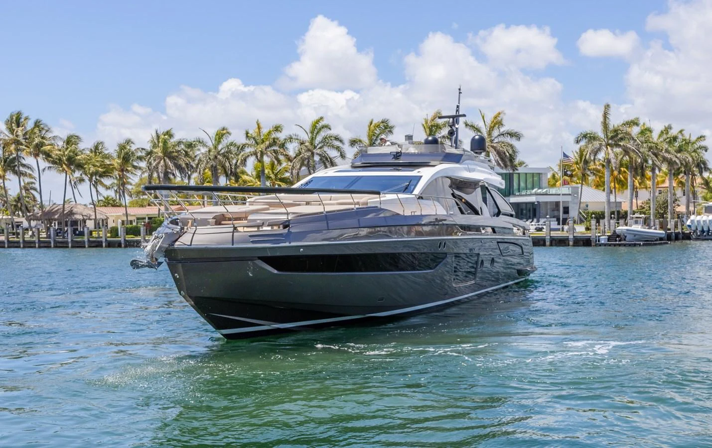 A sleek and modern yacht cruising in a tropical waterfront setting. aboard NO TIME TO DIE Yacht for Sale
