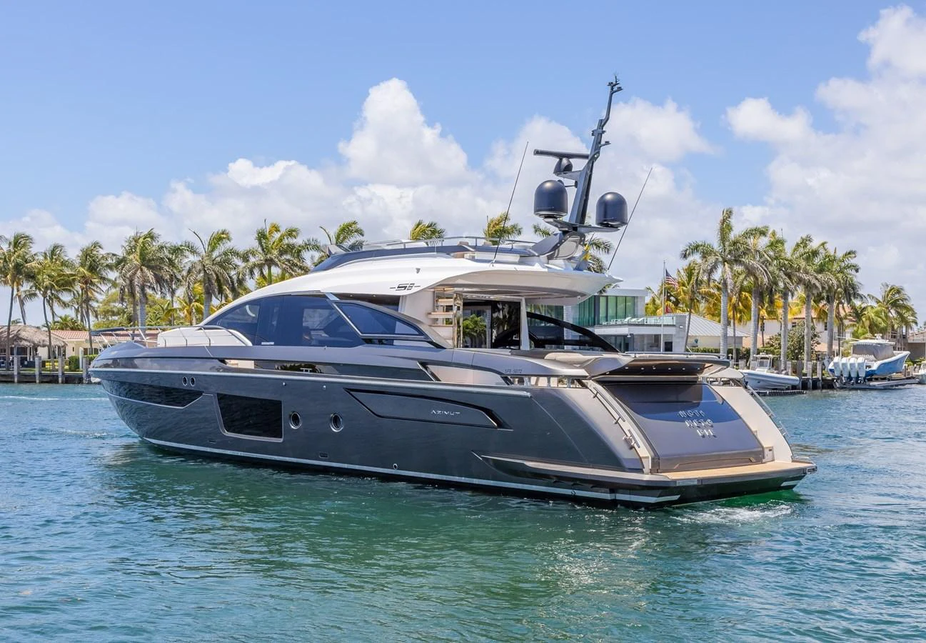 A sleek and modern yacht cruising on calm waters with a backdrop of palm trees and clear skies. aboard NO TIME TO DIE Yacht for Sale