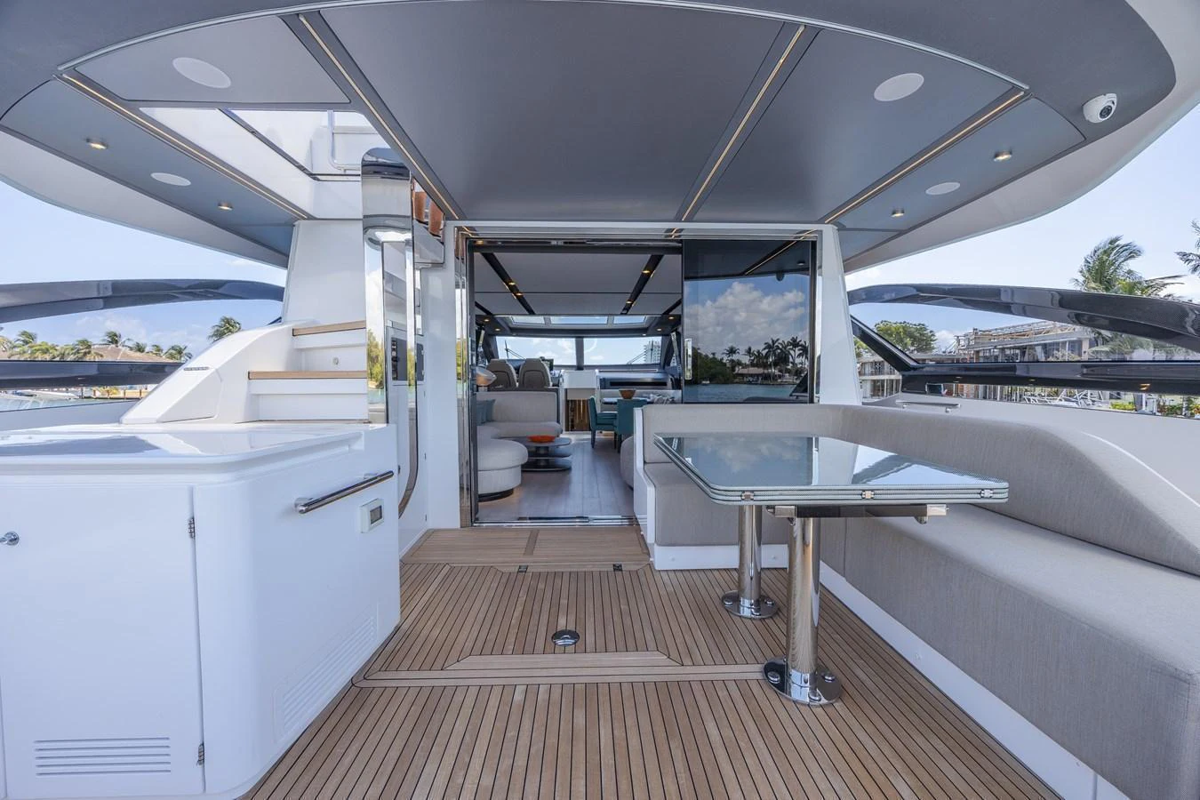 The aft deck features a spacious seating area with a glass table and a seamless transition to the interior living space. aboard NO TIME TO DIE Yacht for Sale